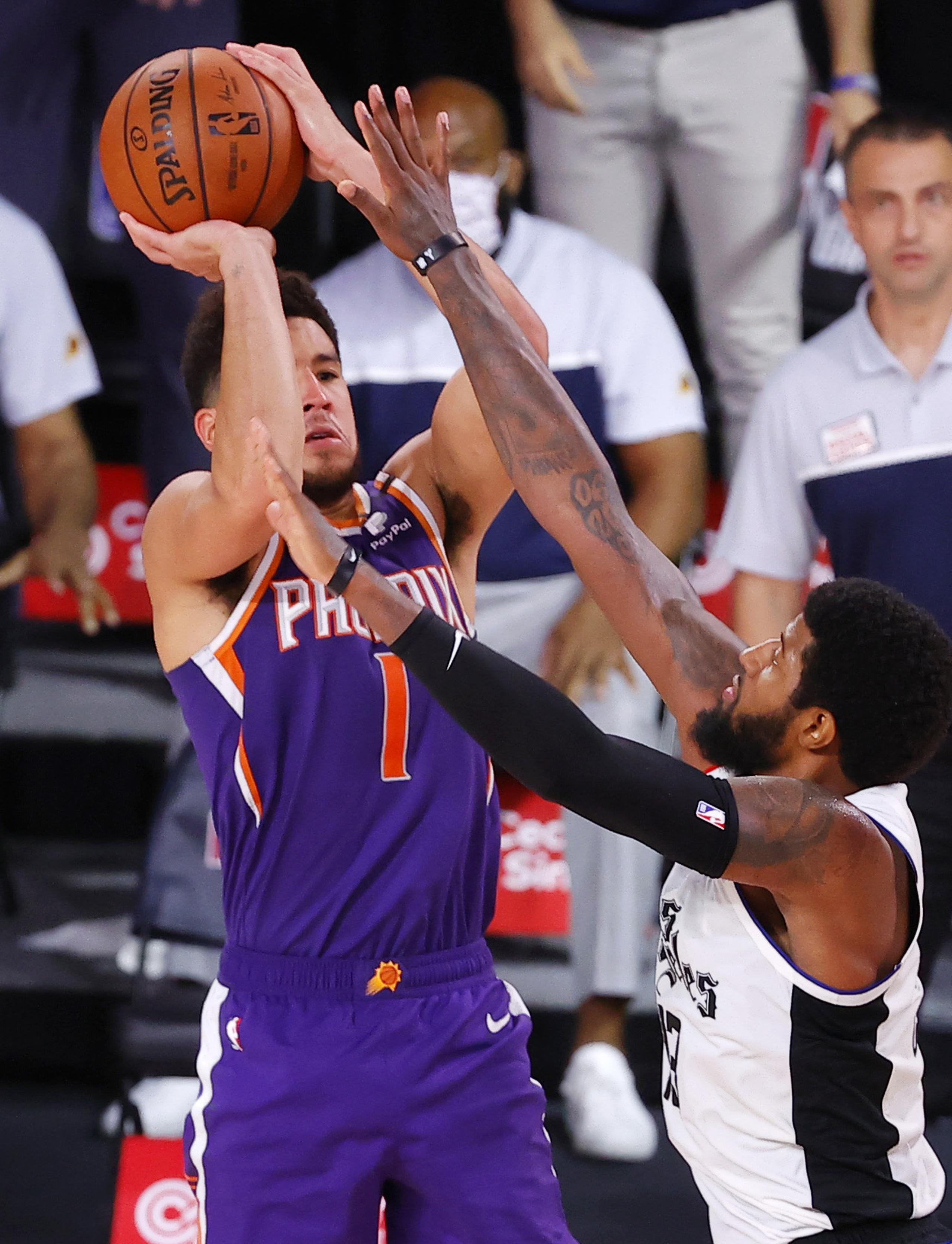 Devin Booker, de los Suns de Phoenix, consigue la canasta del triunfo frente a Paul George, de los Clippers de Los Ángeles, en Lake Buena Vista, Florida, dentro de un partido de la NBA.