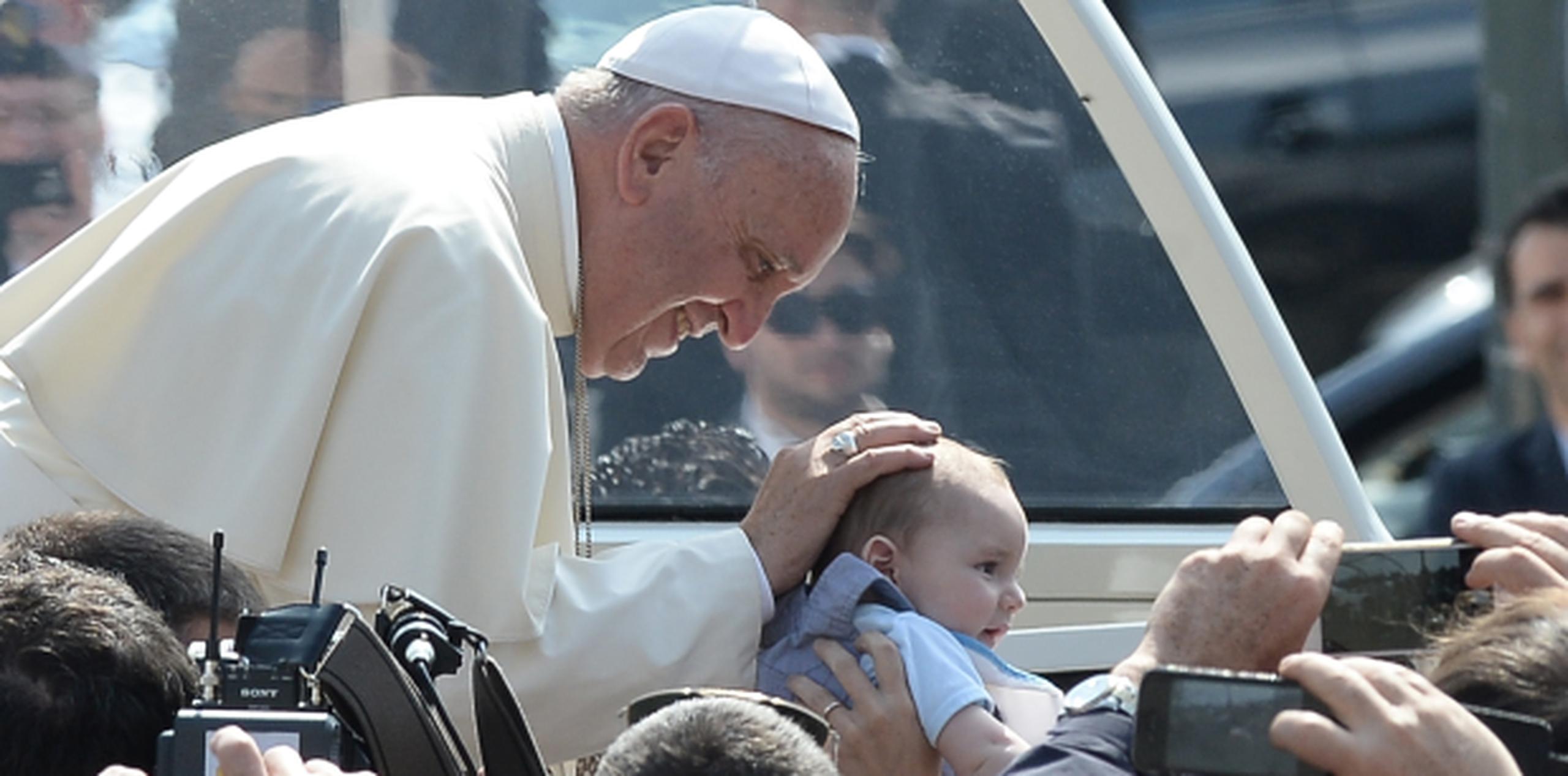 Previo a su mensaje a un grupo de jóvenes hoy en Italia, el sonriente papa Francisco acaricia a un bebé. (AP)