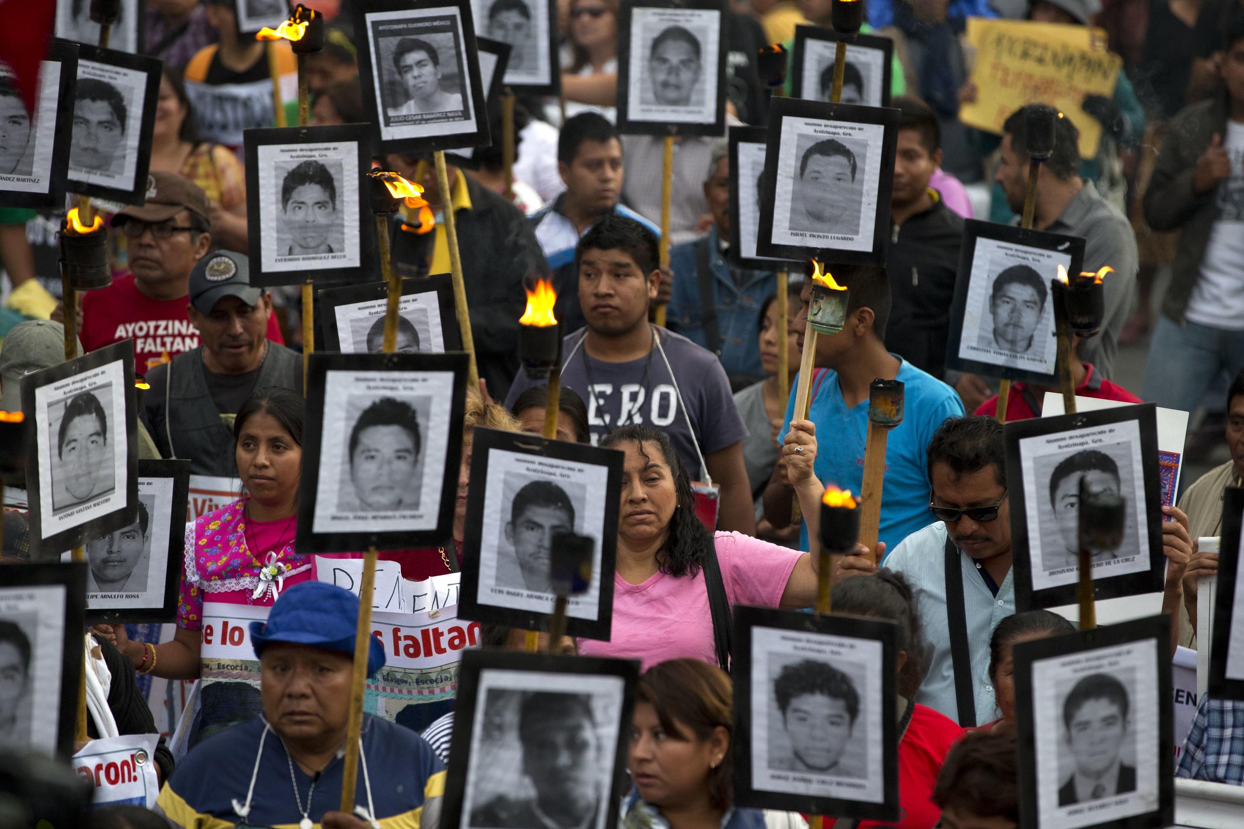 Familiares y activistas de 43 estudiantes normalistas desaparecidos en el estado de Guerrero portan sus retratos para exigir que no se cierre el caso en Ciudad de México.