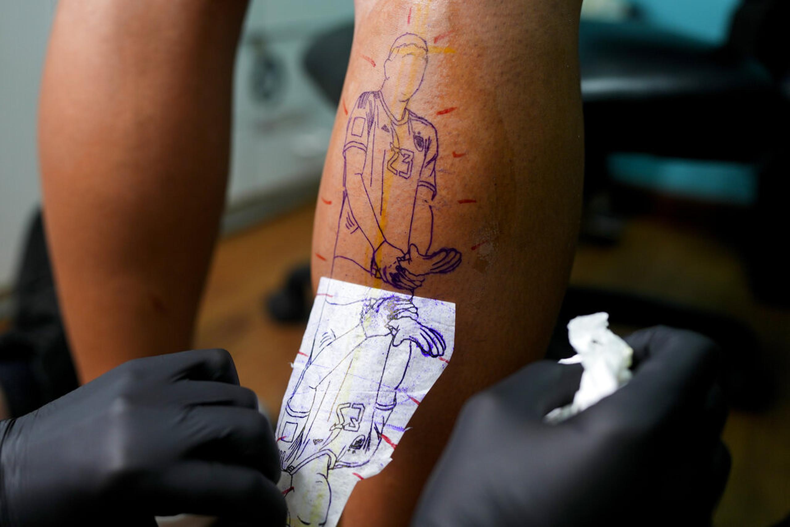El artista Mariano Finkelstein trabaja en un tatuaje del arquero argentino Emiliano Martínez haciendo un gesto con su trofeo de guante de oro durante la ceremonia de premiación de la Copa del Mundo en Qatar 2022, en el cliente Valentin Bobadilla en Buenos Aires, Argentina.