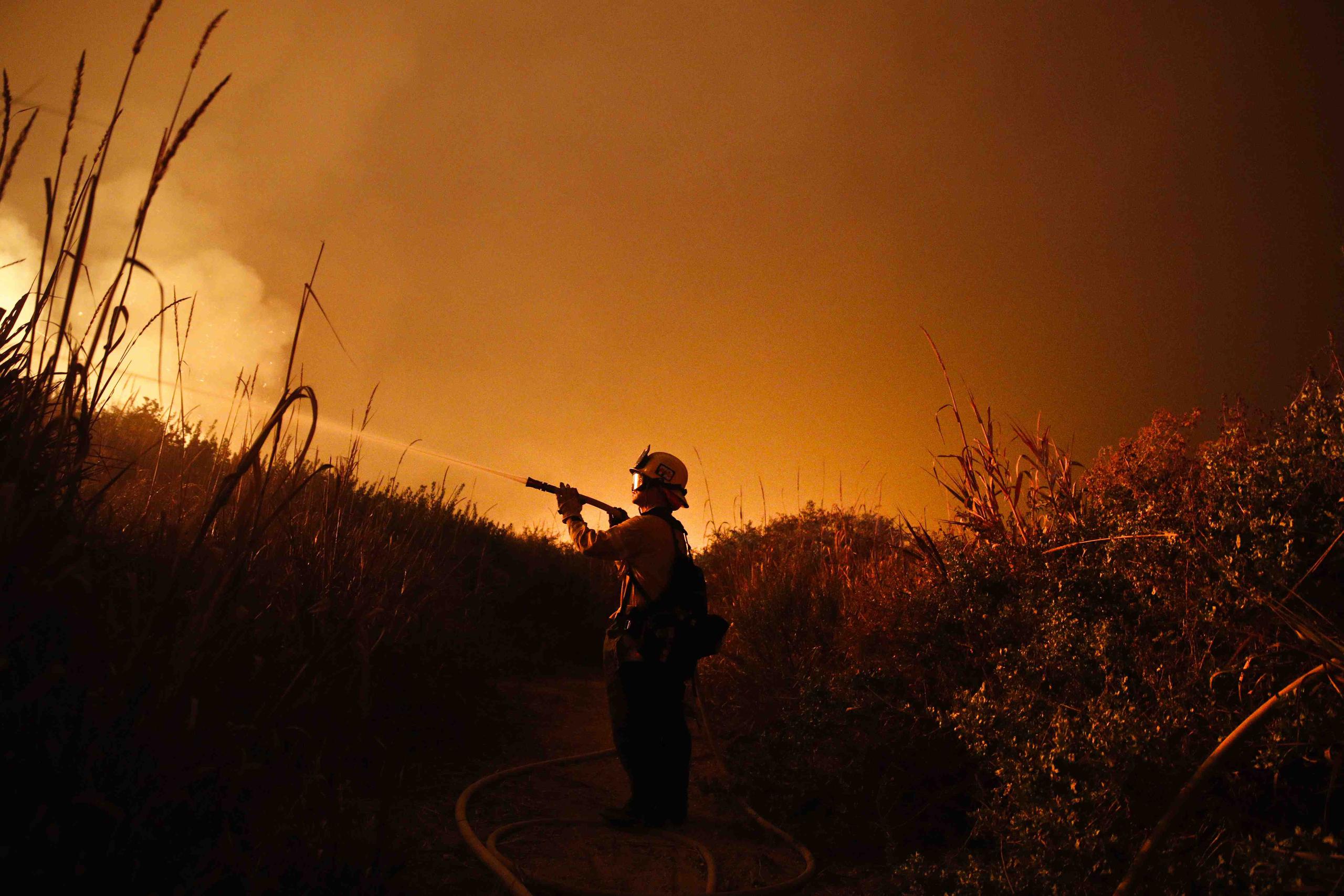 El bombero Ryan Spencer trabaja apagando un incendio en La Conchita, California, el 7 de diciembre de 2017. (Archivo / AP / Jae C. Hong)