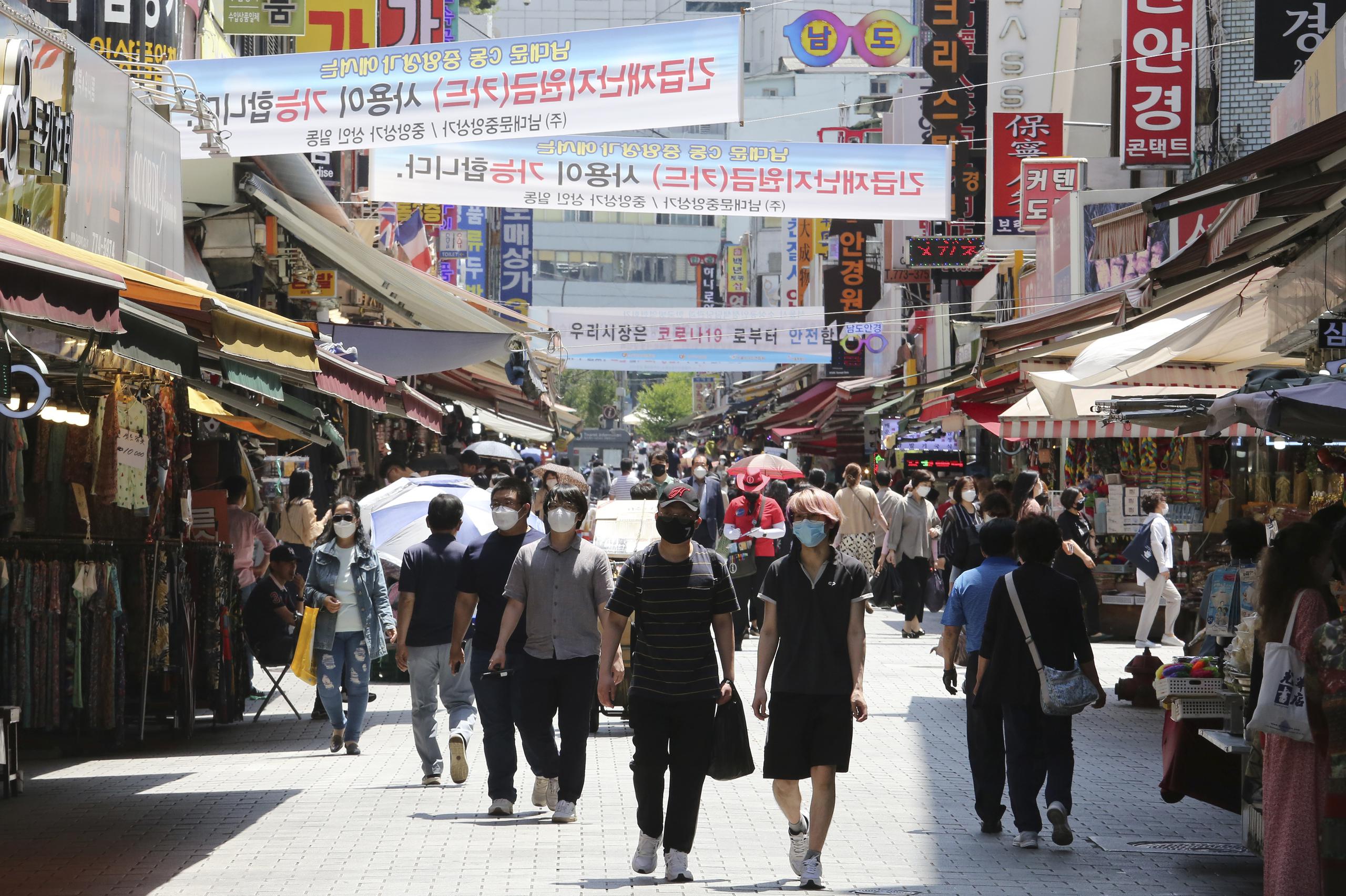 Varias personas caminan por un distrito comercial de Seúl, Corea del Sur