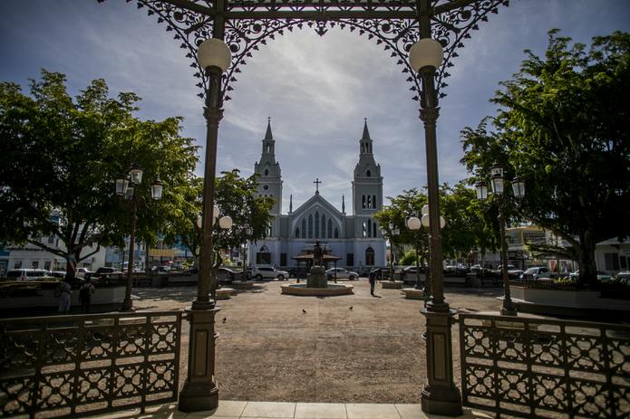 Al fondo de la plaza pública -hoy conocida como la Plaza Almirante Cristóbal Colón- se observa la parroquia San Francisco de Asís, que posee las dos torres más altas entre las antiguas iglesias católicas de Puerto Rico.