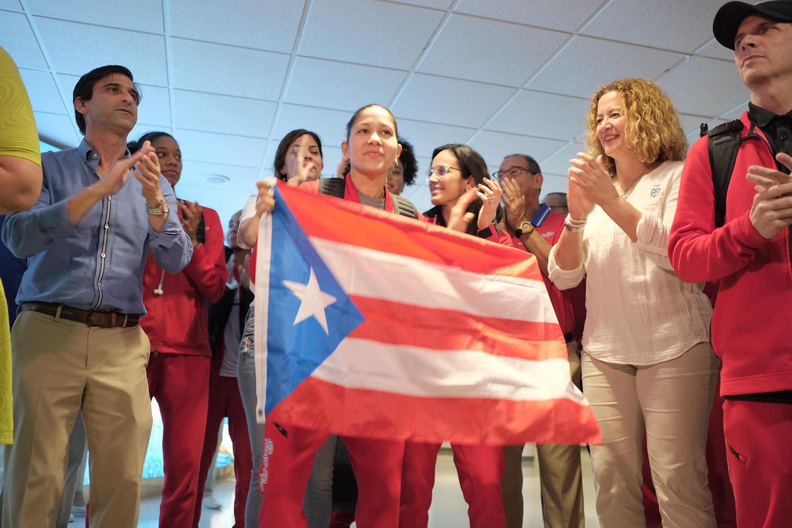 Pamela Rosado sostiene La Monoestrellada durante el recibimiento del lunes del Equipo Nacional de Baloncesto Femenino que se clasificó a las Olimpiadas de Tokio 2020. A su derecha, la presidenta del Comité Olímpico de Puerto Rico, Sara Rosario, y Jerry Batista, dirigente de la escuadra.