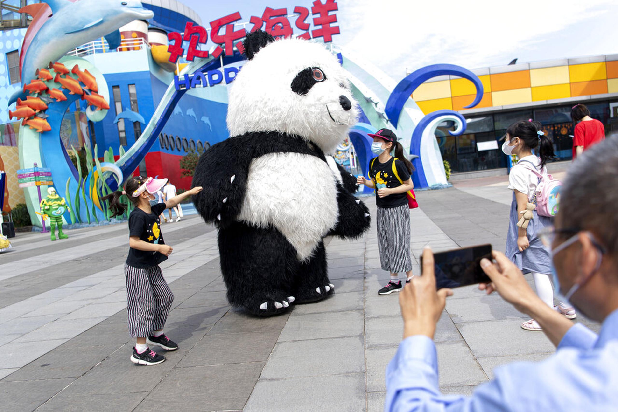 Turistas se tomaron fotos con una mascota del parque temático Happy Valley Wuhan el pasado martes.
