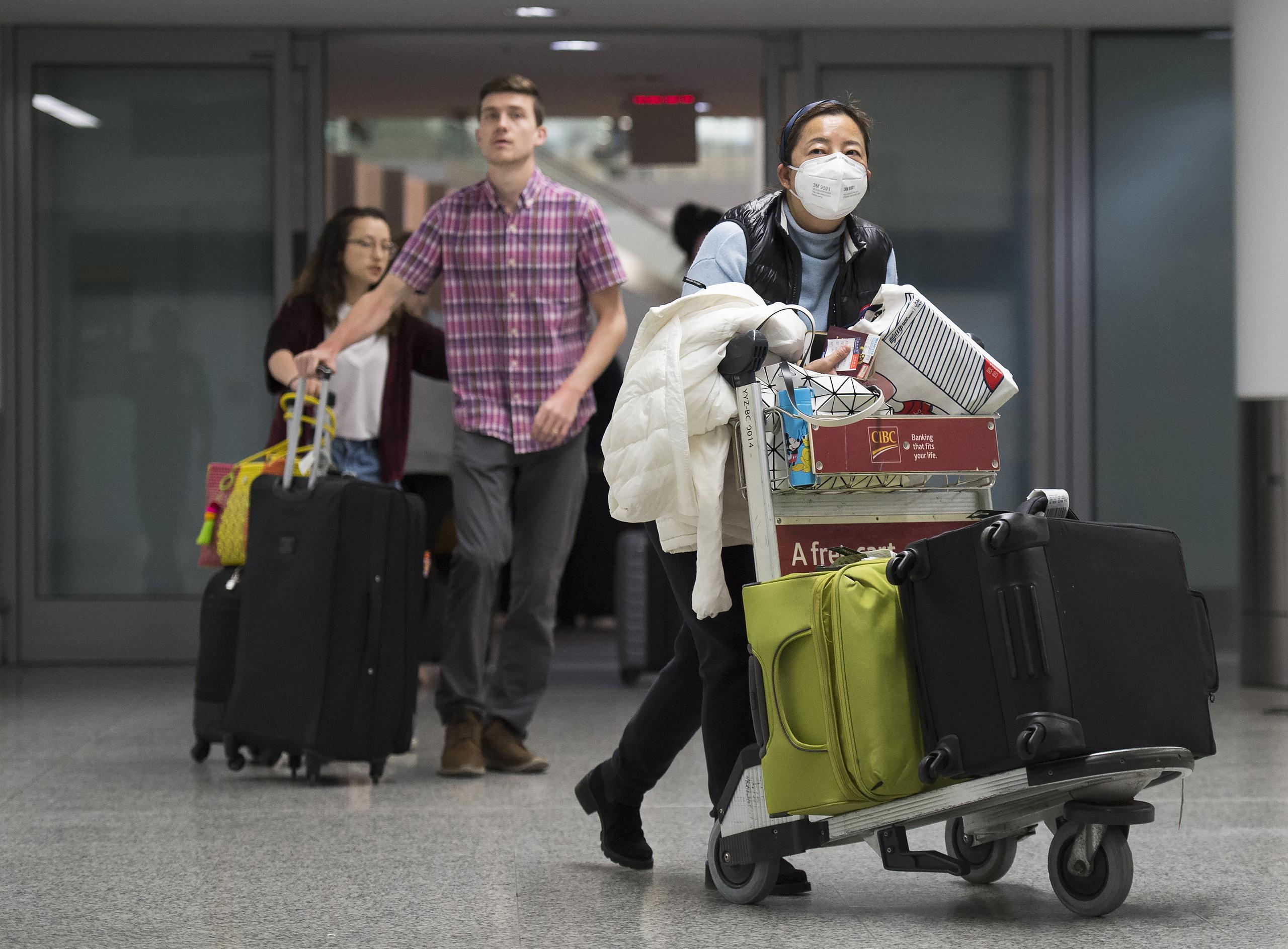 Una mujer con mascarilla camina en la zona de llegadas de la terminal internacional del aeropuerto Toronto Pearson, Canadá