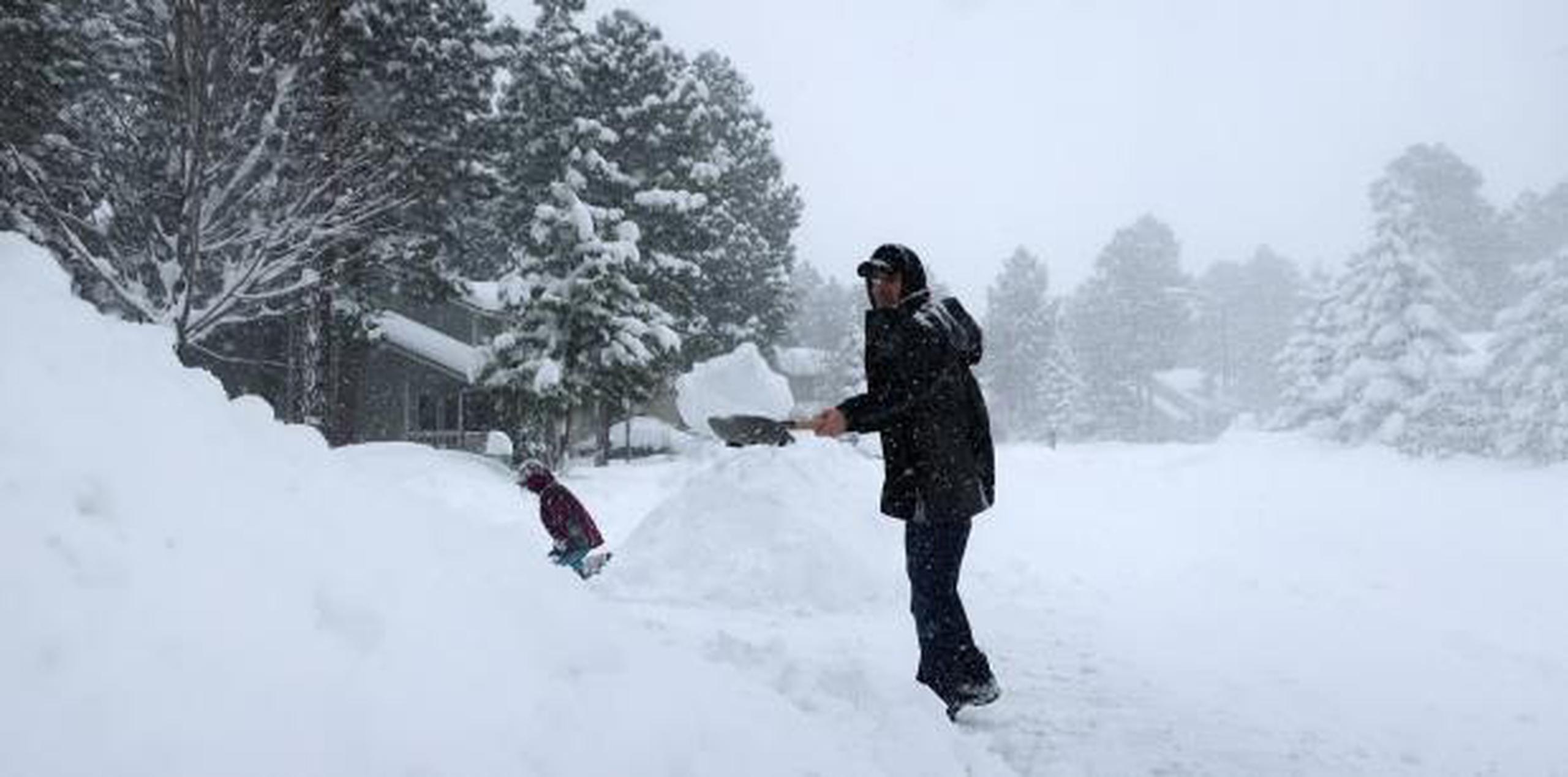 Morgan Baggs sacaba la nieve del frente de su casa mientras nevaba ayer, jueves, en Flagstaff, Arizona. (AP / Felicia Fonseca)