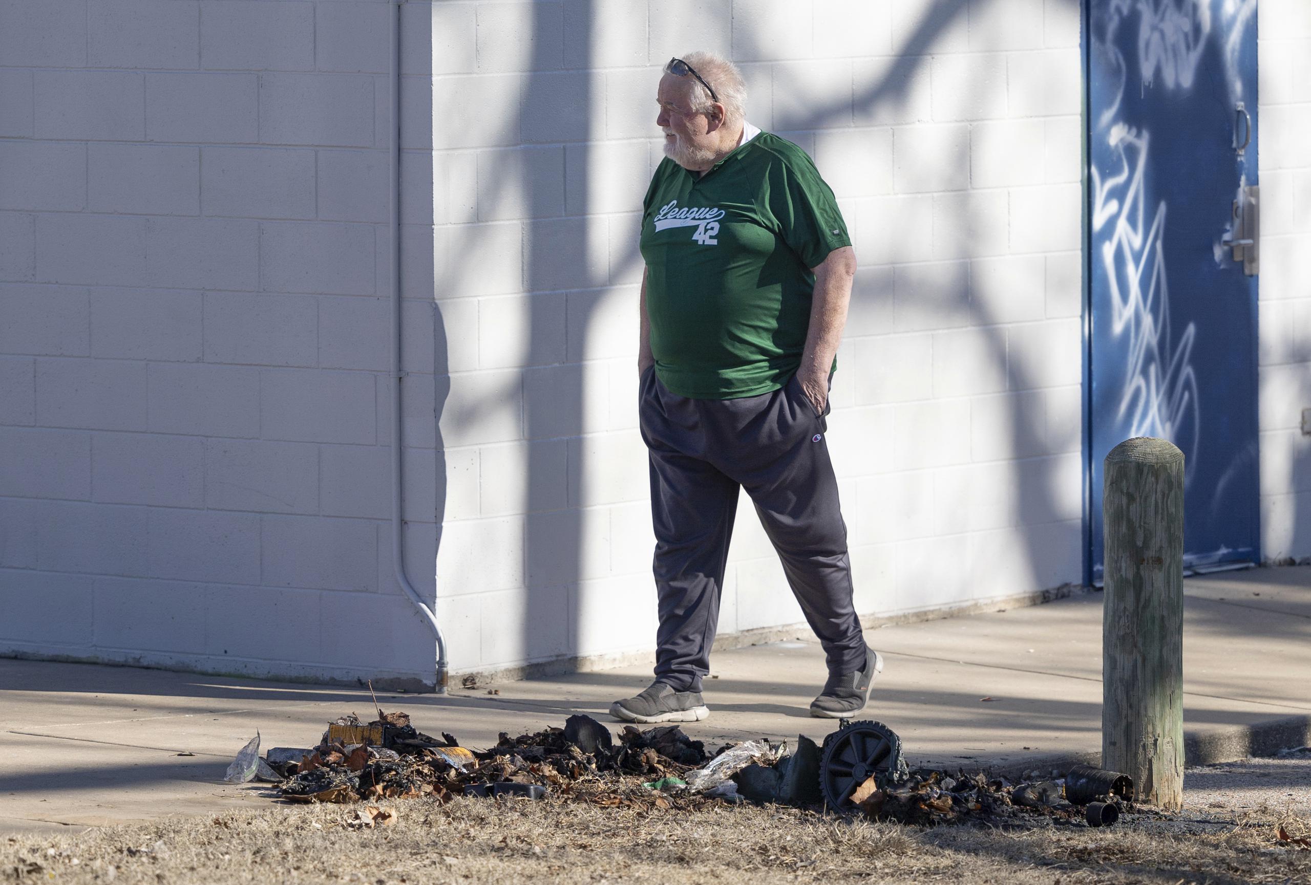 Bob Lutz, director ejecutivo de Liga 42, una liga de béisbol juvenil en Wichita, Kansas, camina junto a los restos carbonizados de un contenedor de basura donde la policía de Wichita encontró piezas de una estatua robada de Jackie Robinson el martes 30 de enero de 2024. 