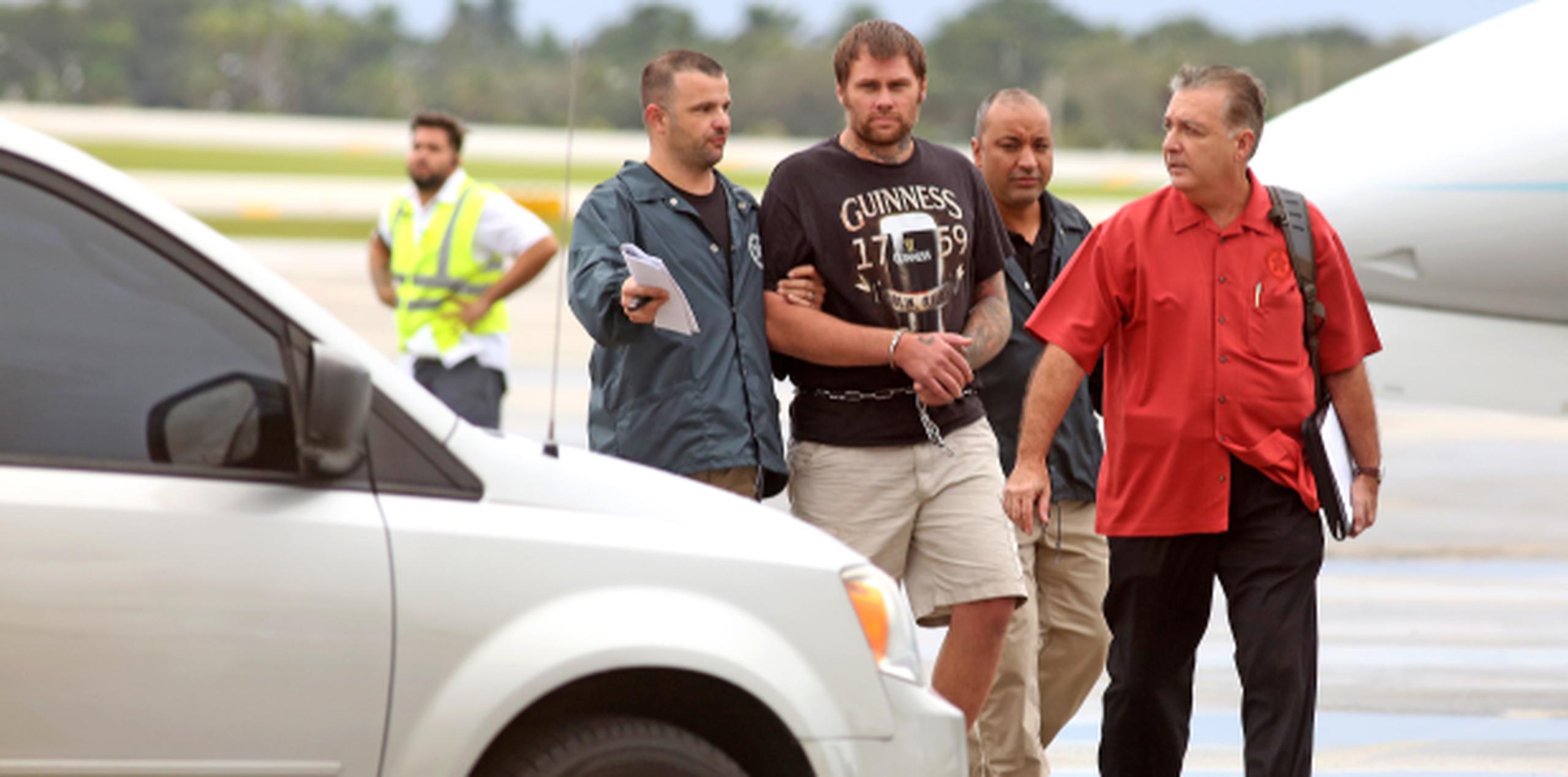 Algauciles federales escoltan a Shawn Wegmann en el aeropuerto de Fort Lauderdale/Hollywood, a donde fue llevado luego que lo entregaran las autoridades cubanas. (Susan Stocker/South Florida Sun-Sentinel via AP)