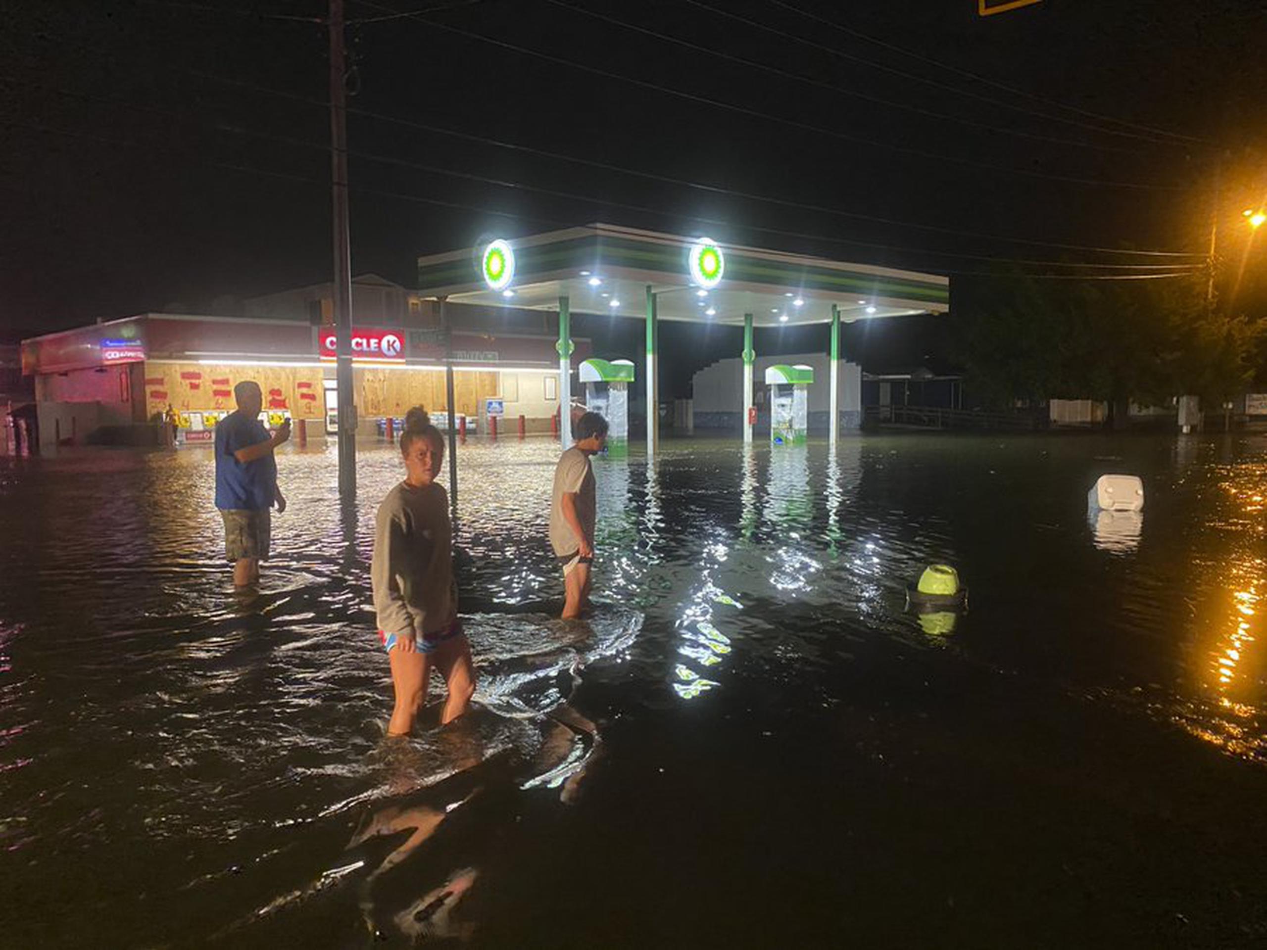 Ciudadanos caminan en un área parcialmente inundada por las aguas que trajó la ahora tormenta isaías.
