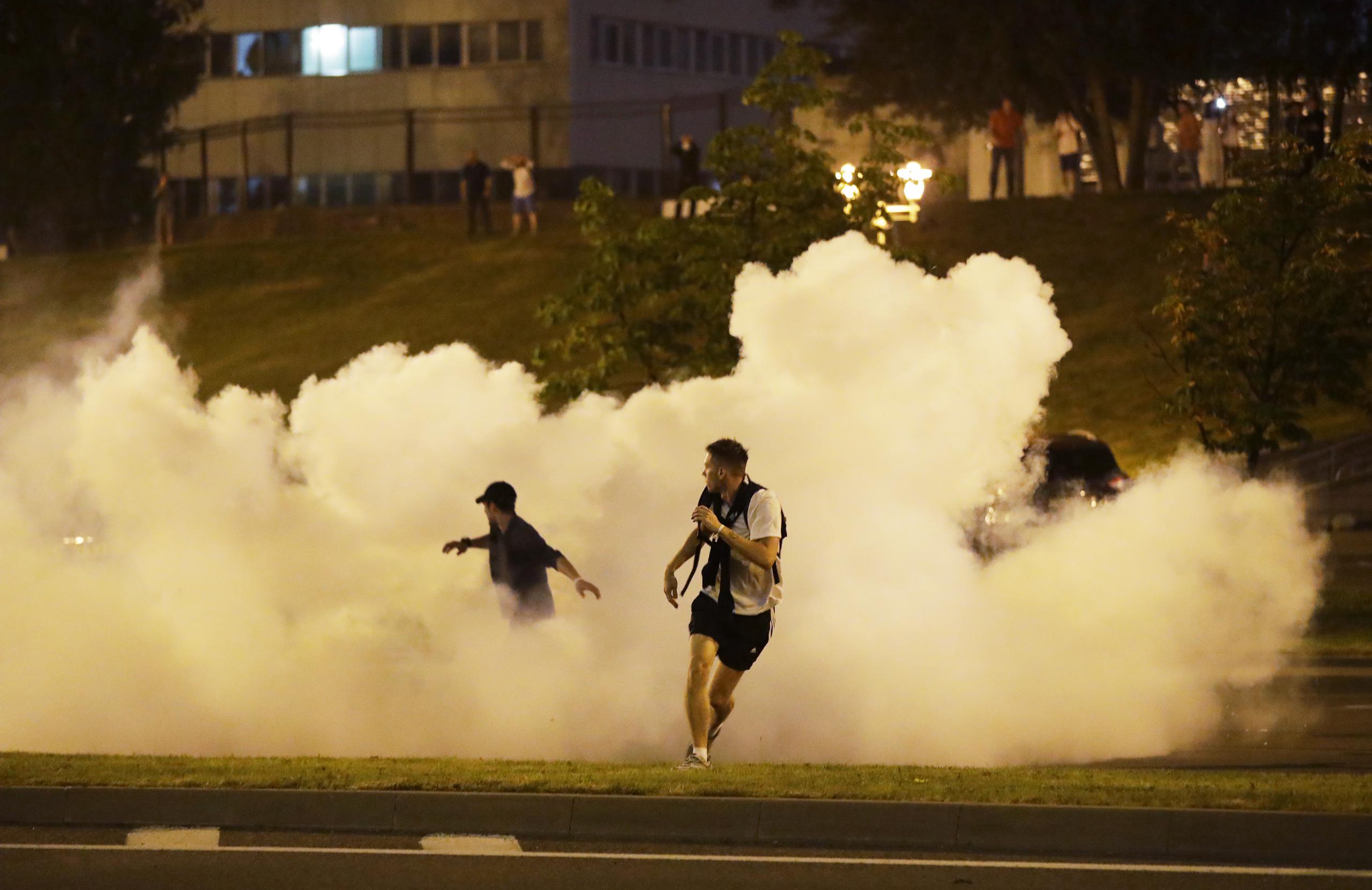 Manifestantes corren en medio del humo durante una protesta tras las elecciones presidenciales, en Minsk, Bielorrusia