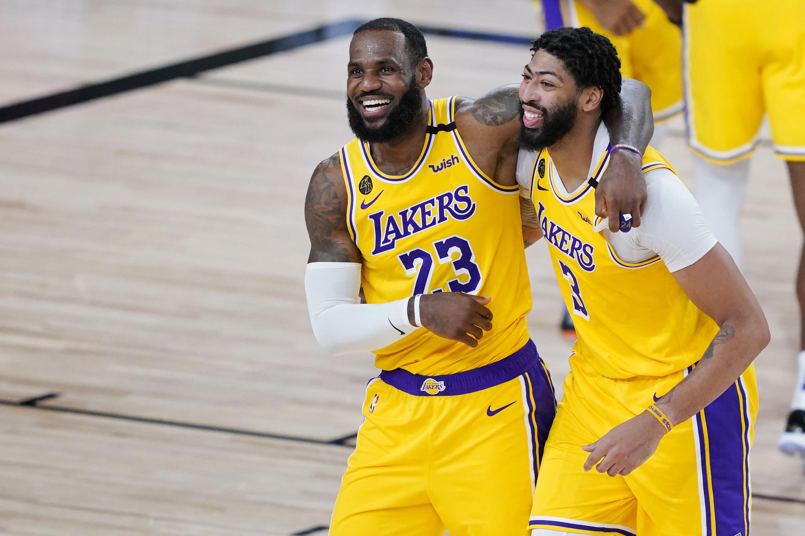 LeBron James (23) y Anthony Davis (3) de los Lakers de Los Ángeles celebran tras la victoria ante los Nuggets de Denver, el lunes 10 de agosto de 2020.