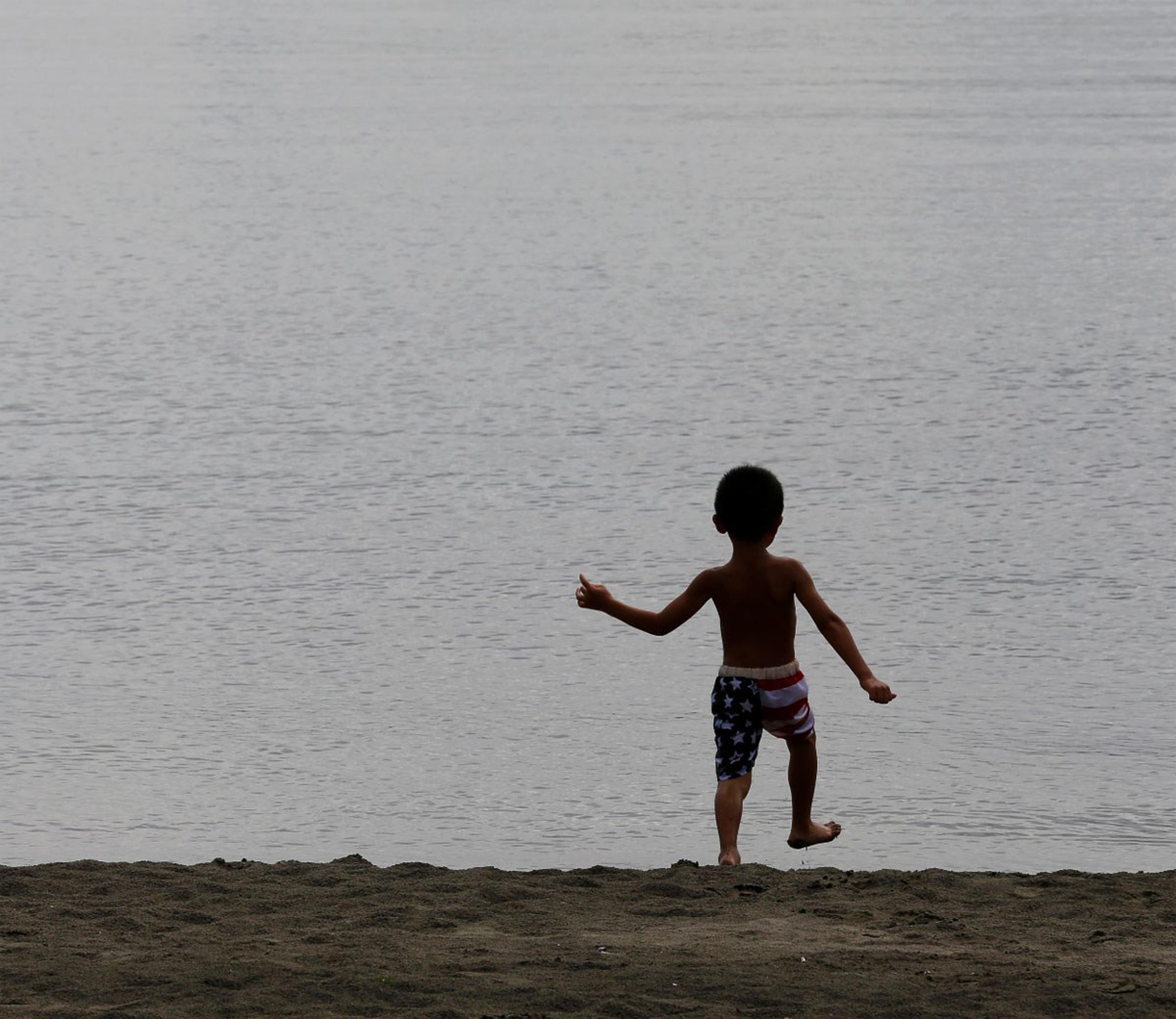 Un pequeño juega a la orilla de la playa mientras la ola de calor hace estragos. (AP)