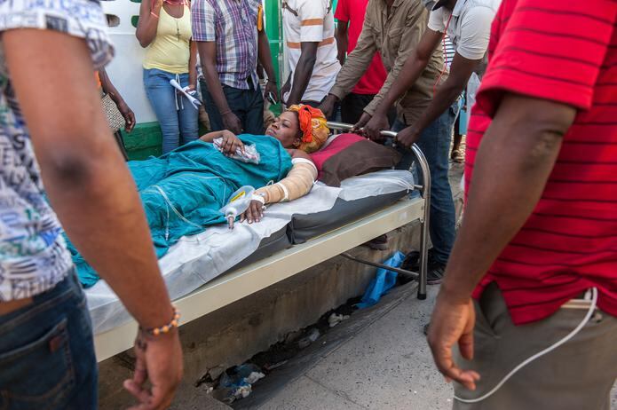 Unas personas cargan la camilla en la que permanece una mujer herida tras una explosión en Cap Haitien (Haití), el pasado 14 de diciembre de 2021. EFE/Johnson Sabin
