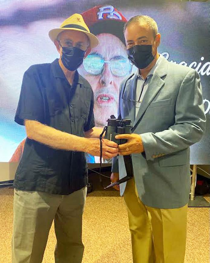 Norman H. Dávila (izquierda) le entrega a Joe Bruno (derecha) unos binoculares.