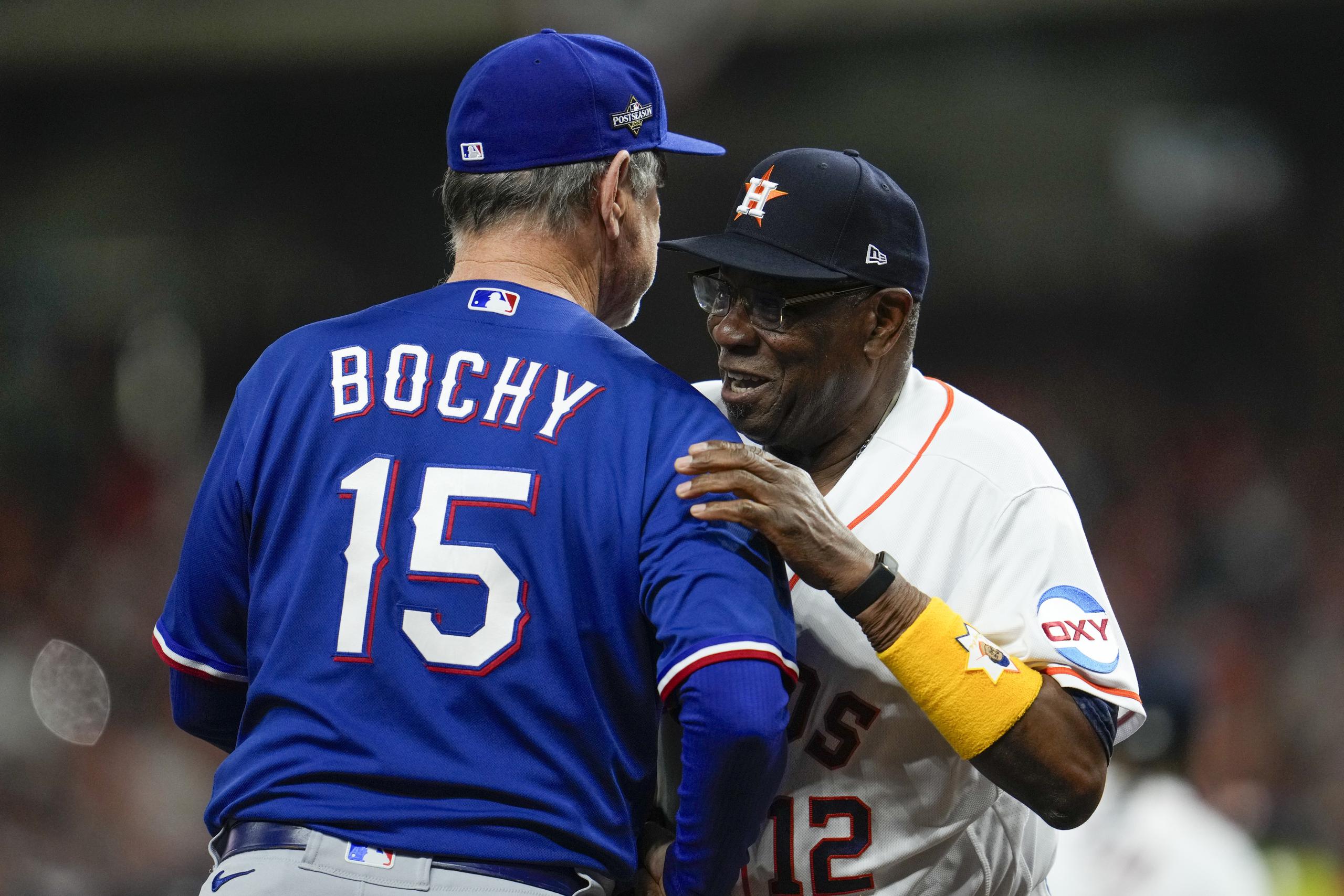 El dirigente de los Astros, Dusty Baker, de frente, abraza a su contraparte de los Rangers, Bruce Bochy. Ambos son el uno y dos entre los mánagers con más edad en MLB en la actualidad, esto con 74 y 68 años, respectivamente.