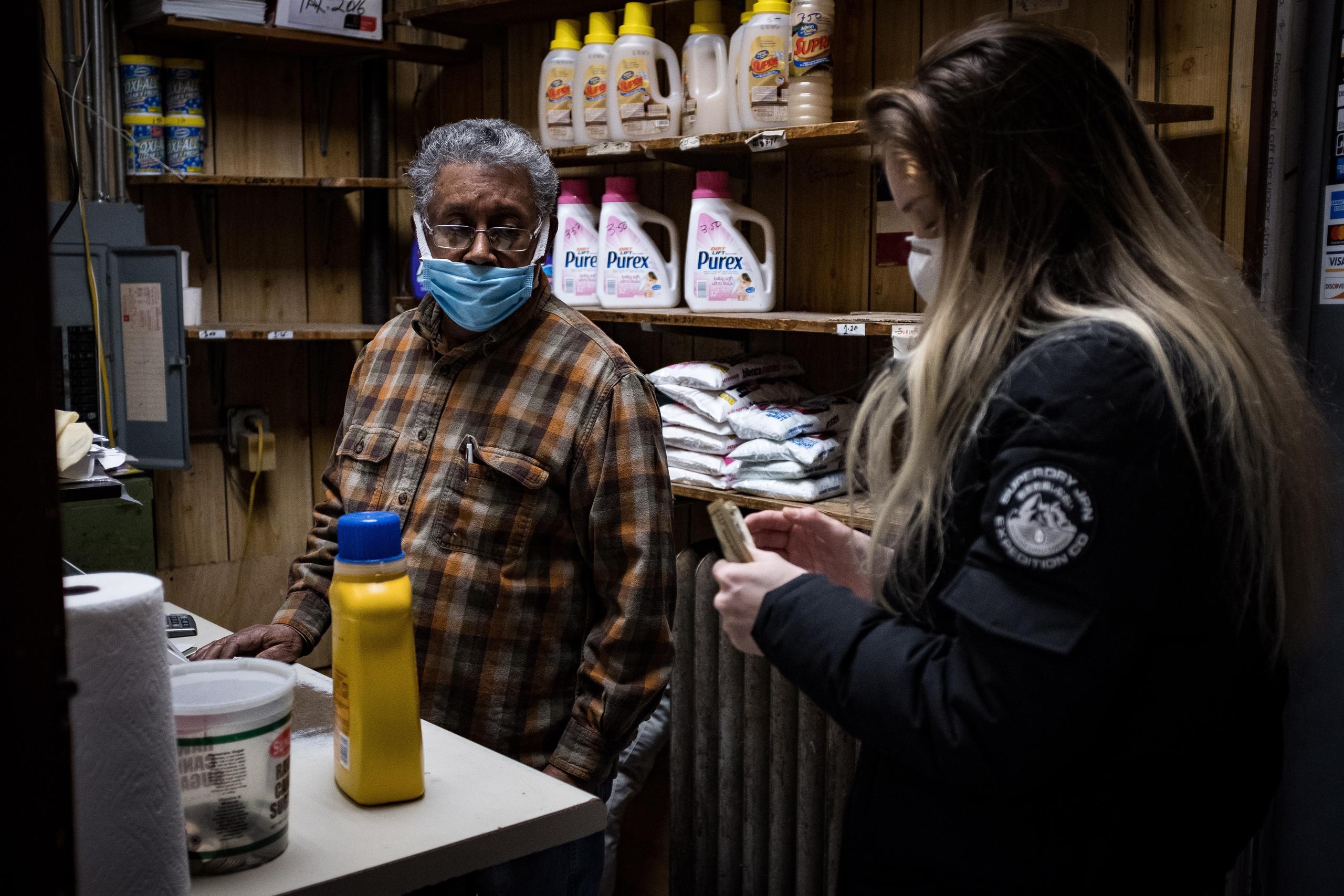 Ismael Taveras (i) mientras atiende a una clienta en el 'Graham Laundromat', el negocio familiar en el que trabaja en Brooklyn, Nueva York (EE.UU.).