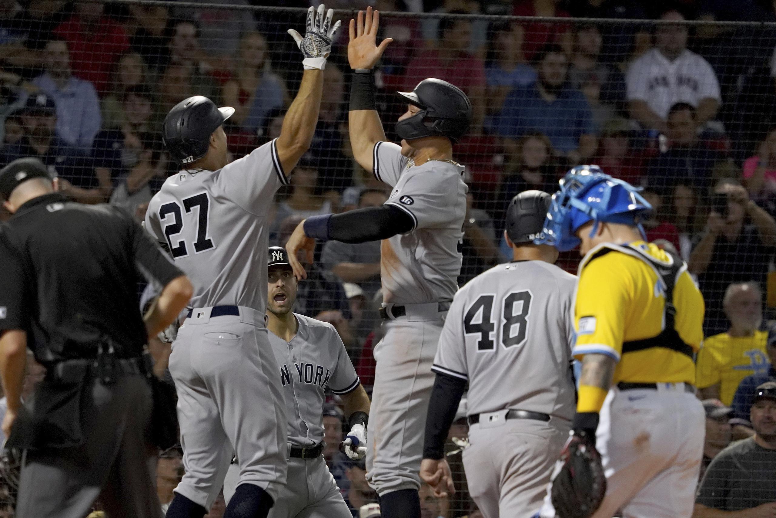 El bateador designado de los Yankees de Nueva York, Giancarlo Stanton (27), celebra con Aaron Judge tras disparar un bambinazo de tres carreras durante la tercera entrada del partido del viernes en el Fenway Park de Boston.