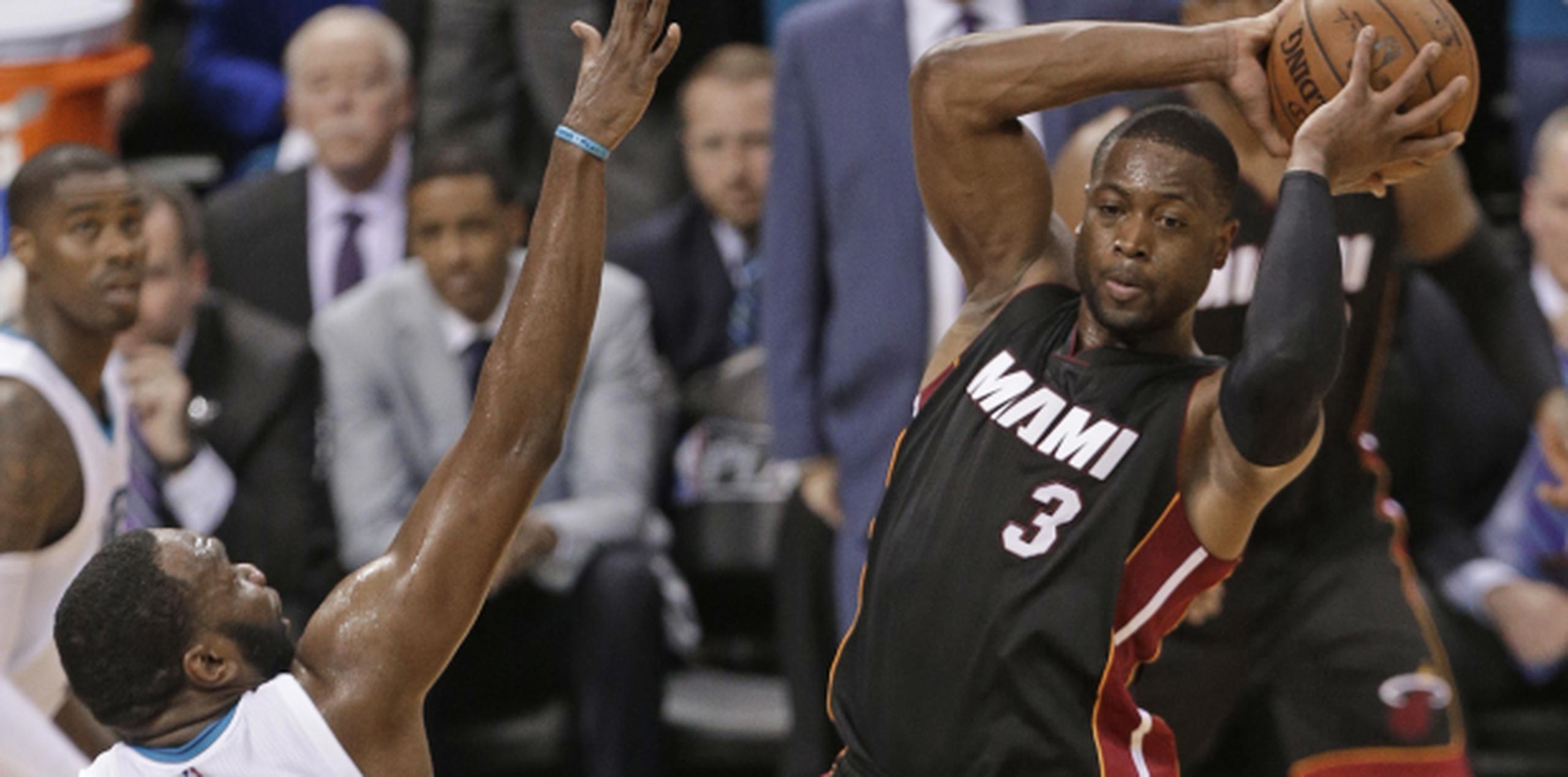 Dwyane Wade busca un compañero para pasar el balón en la victoria del Heat ante los Hornets. Wade encabezó el ataque de Miami con 23 puntos.(AP/Chuck Burton)