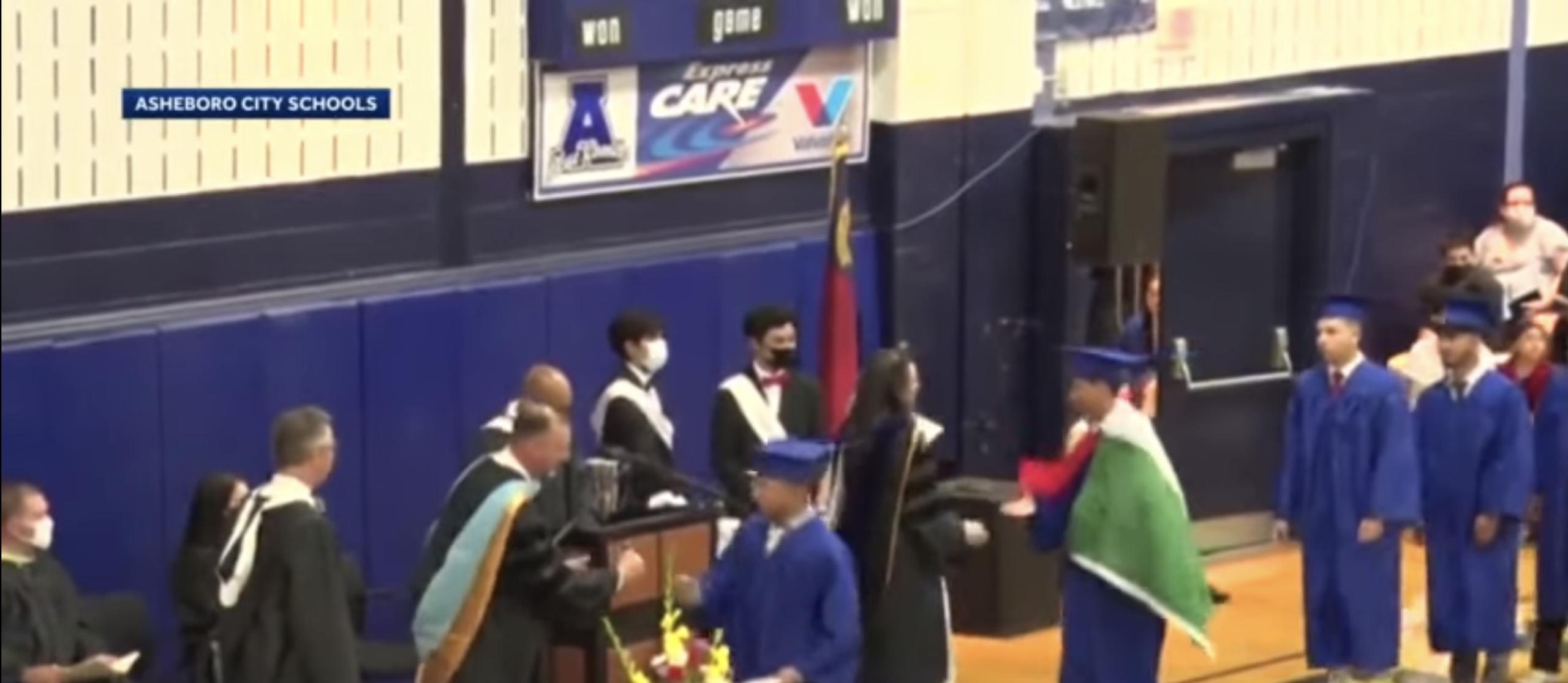 Momento en el que el alumno va a recoger su diploma con la bandera en sus hombros.