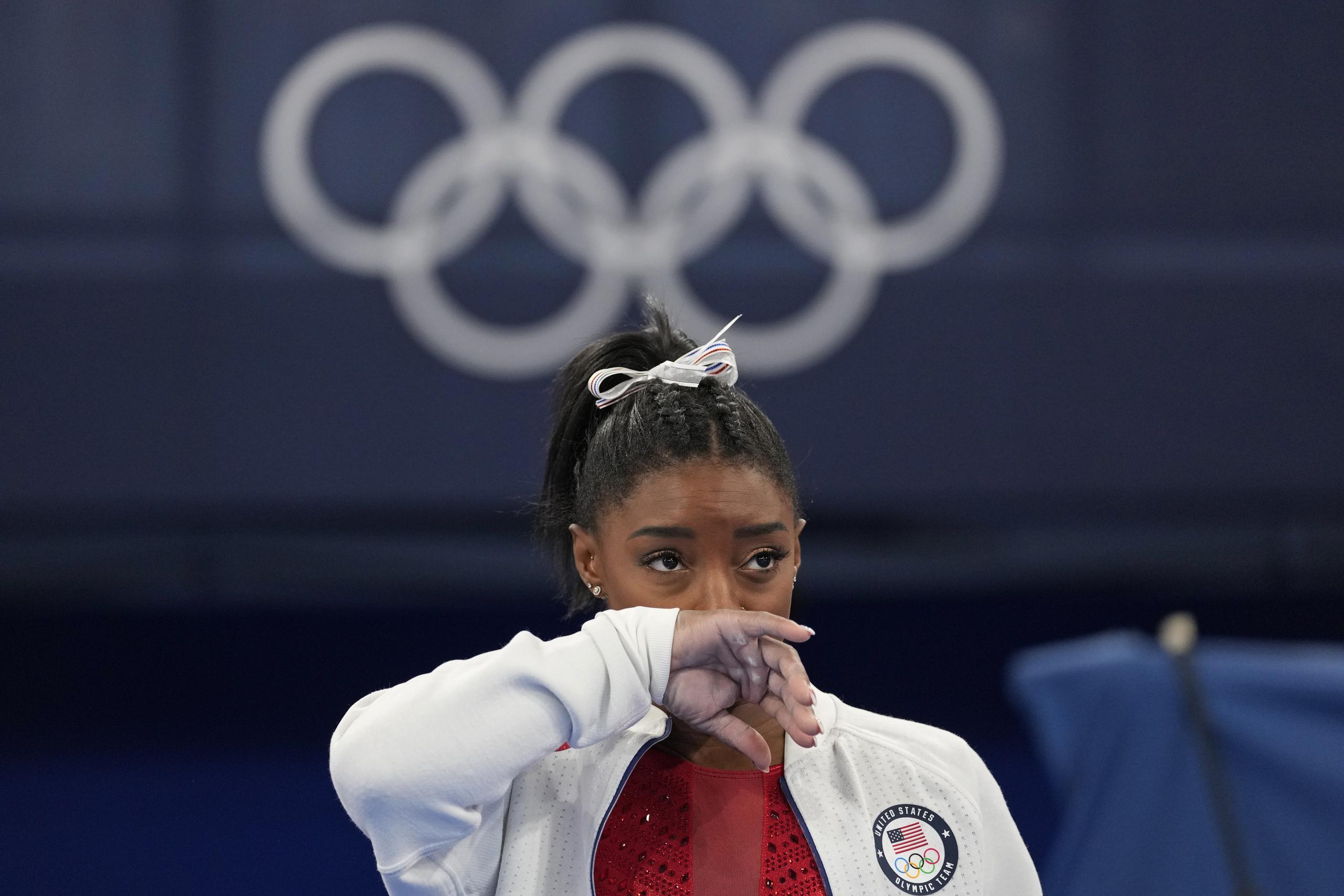 La estadounidense Simone Biles observa la actuación de otras gimnastas tras retirarse de la final por equipos de los Juegos de Tokio 2020 por una aparente lesión.
