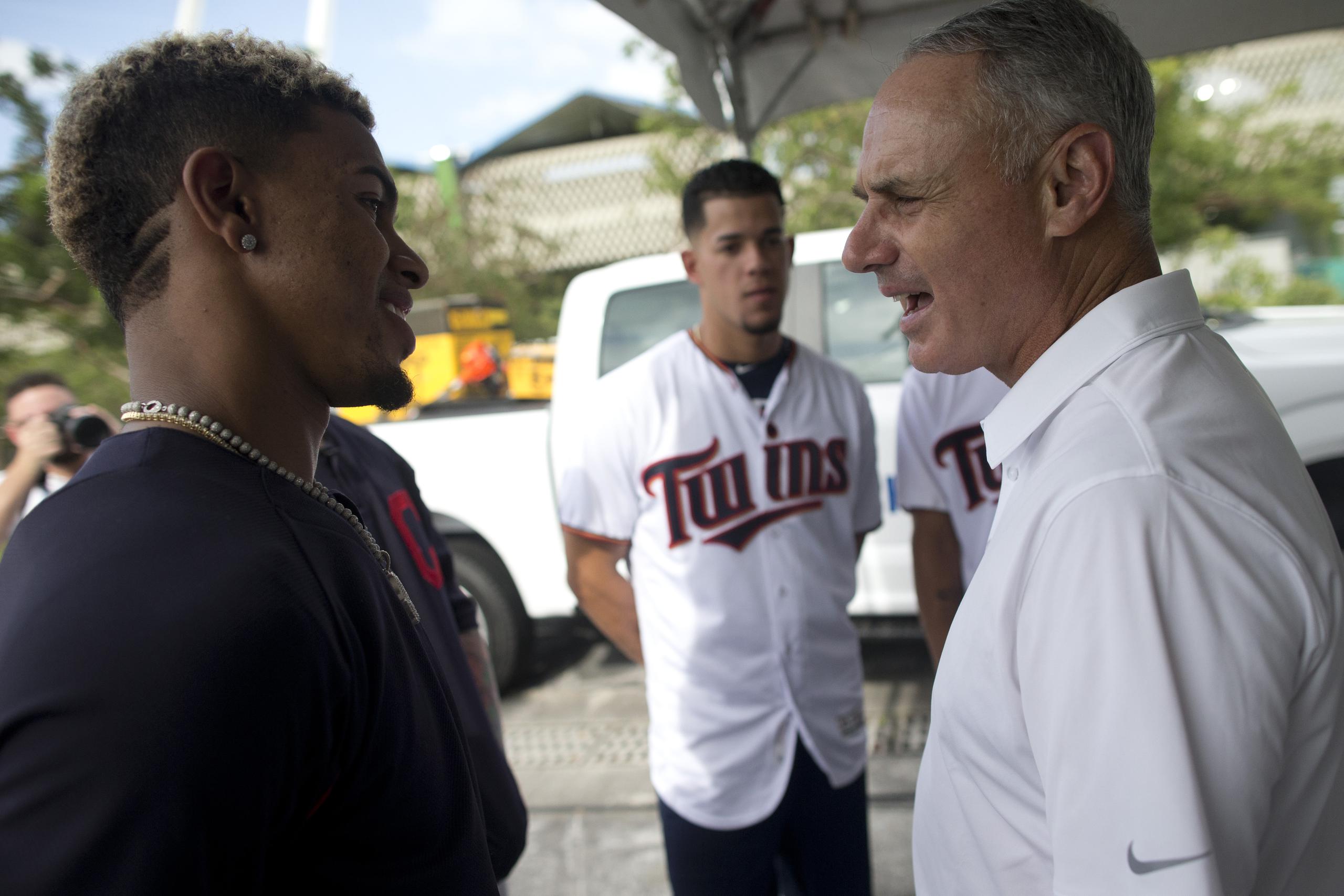 El comisionado de MLB, Rob Manfred, en la foto a la derecha conversando con Francisco Lindor, anunció la iniciativa de los 30 clubes de donar $1 millón cada uno y ayudar a los empleados.