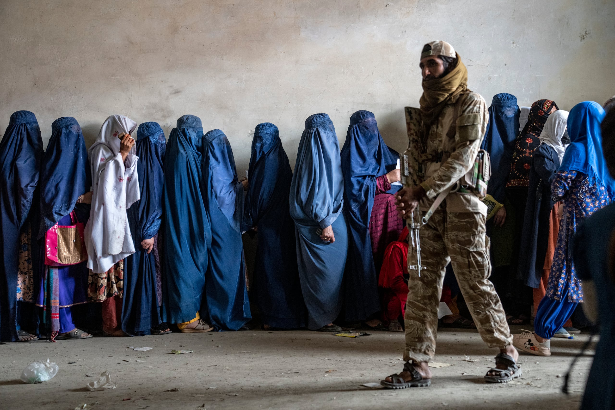 Un combatiente del Talibán monta guardia mientras mujeres esperan a recibir raciones de comida (AP Foto/Ebrahim Noroozi, Archivo)