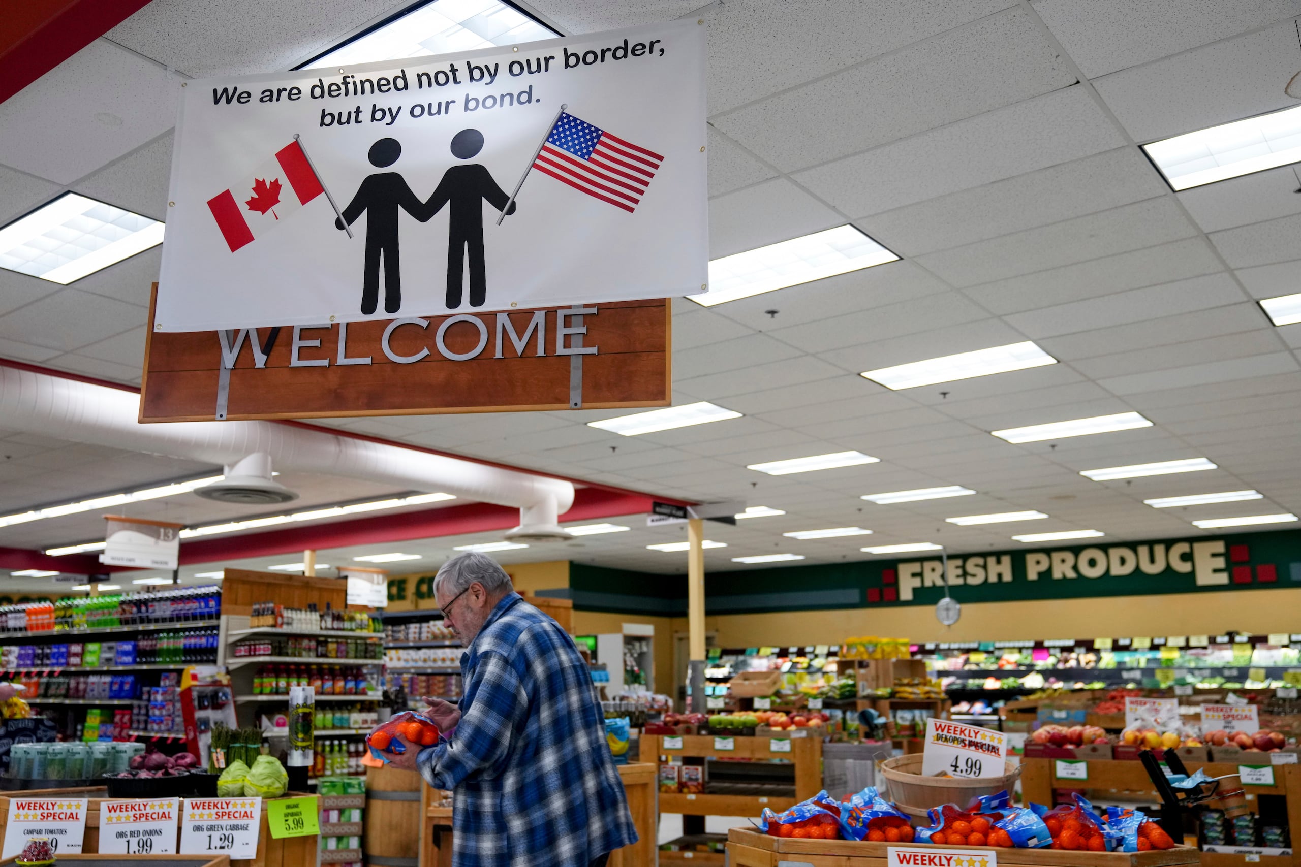 Un cliente en el Mercado Internacional de Point Roberts inspecciona una bolsa de naranjas el martes 18 de marzo de 2025 en Washington, en la frontera con Canadá. (AP Foto/Lindsey Wasson)