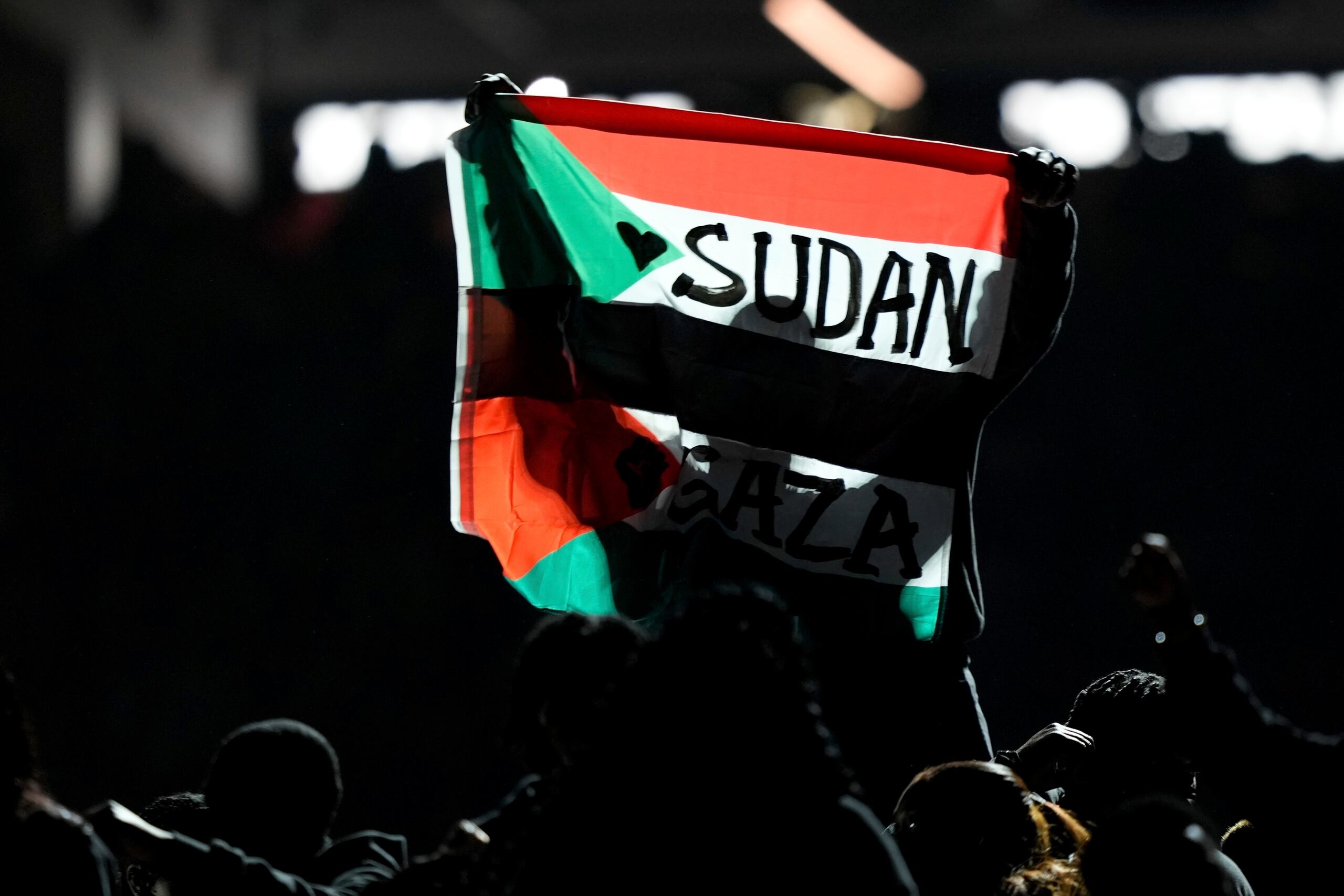Un individuo alza una bandera que menciona a Sudán y Gaza durante el descanso del Super Bowl, el 9 de febrero de 2025, en Nueva Orleans.