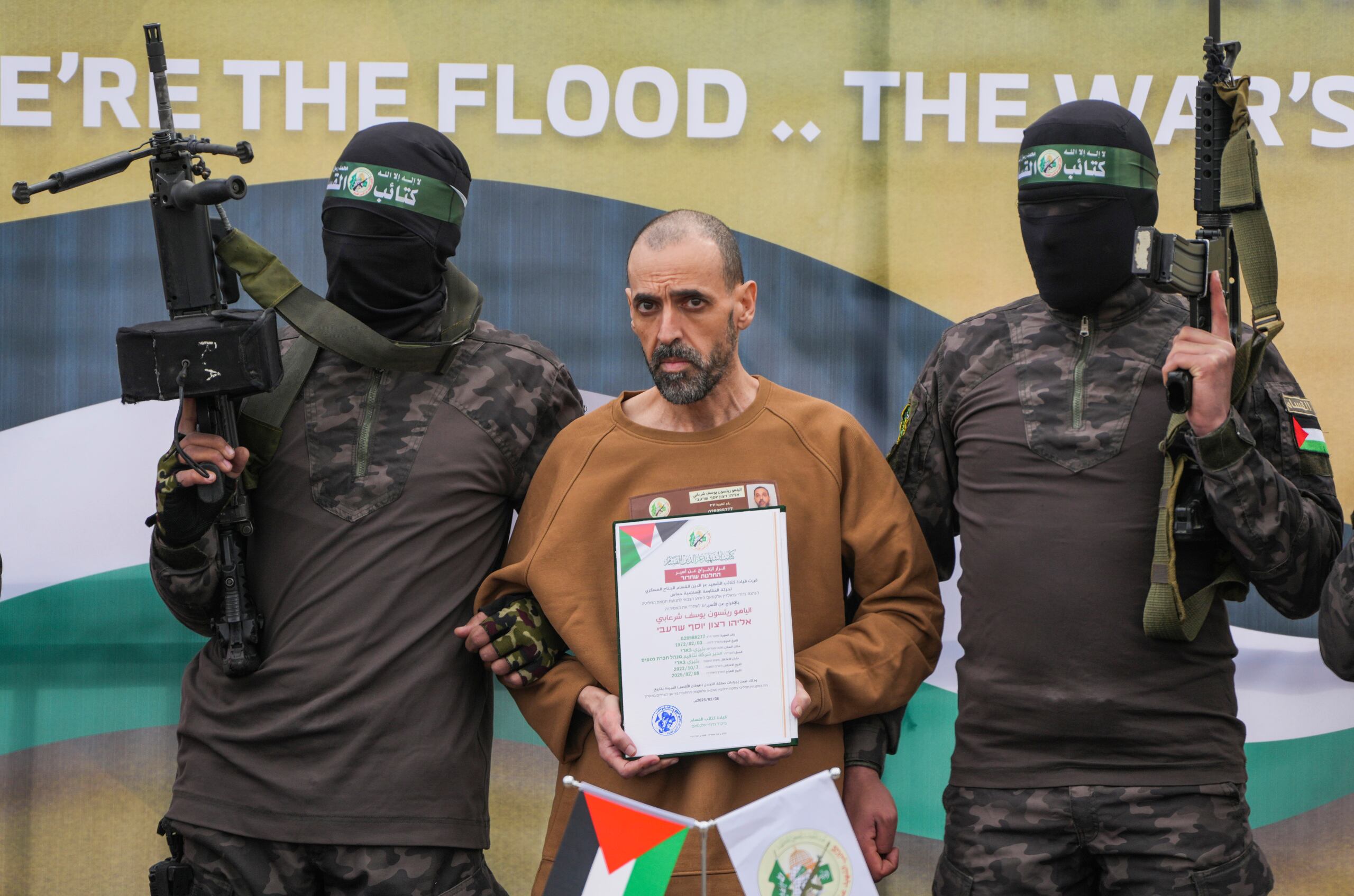El cautivo israelí Eli Sharabi, que ha estado retenido como rehén por Hamas en Gaza desde el 7 de octubre de 2023, se encuentra en un escenario escoltado por combatientes de Hamas antes de ser entregado a la Cruz Roja en Deir al-Balah, en el centro de la Franja de Gaza, el sábado 8 de febrero de 2025. (Foto AP/Abdel Kareem Hana)