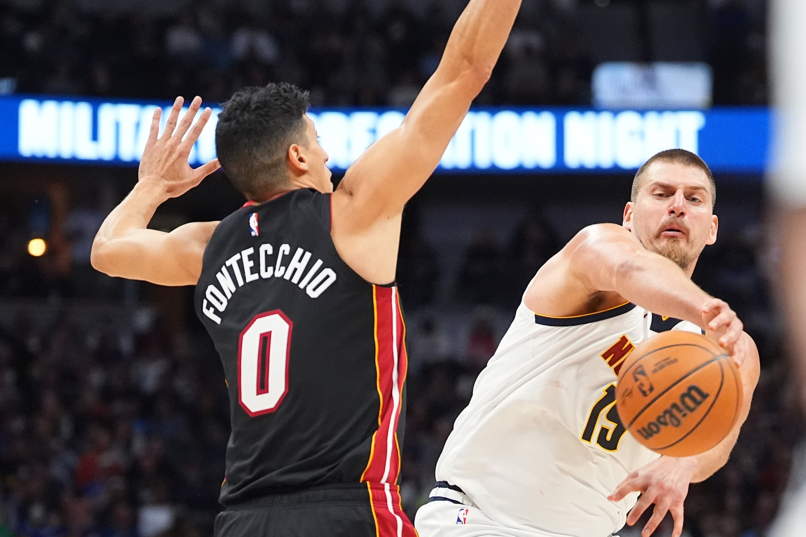 Nikola Jokic, derecha, de los Nuggets de Denver, pasa el balón mientras Simone Fontecchio (0), del Heat de Miami, defiende durante la segunda mitad del partido de baloncesto de la NBA el miércoles 5 de noviembre de 2025, en Denver. (AP Foto/David Zalubowski)