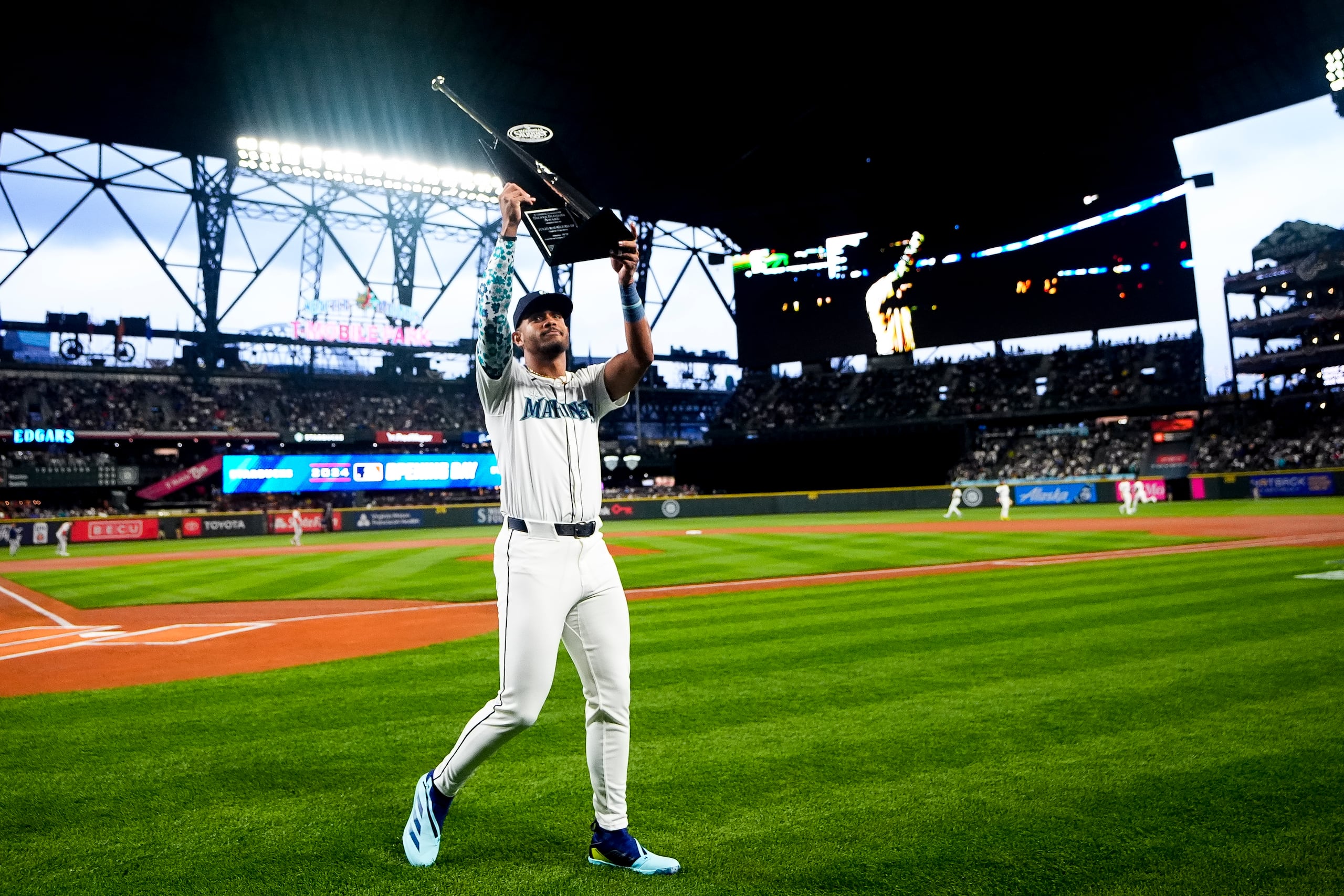 El jardinero central de los Marineros de Seattle Julio Rodríguez sostiene el trofeo al toletero de plata de la temporada pasada durante el Día Inaugural en el encuentro ante los Red Sox de Boston el jueves.