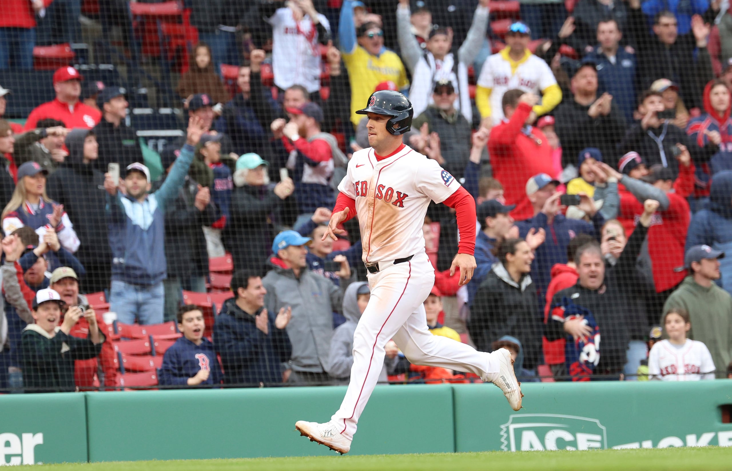 Aficionados de los Red Sox celebran a Alex Bregman mientras recorre las bases tras el sencillo remolcador de Wilyer Abreu en la décima del primer juego de la doble cartelera ante los Cardinals.