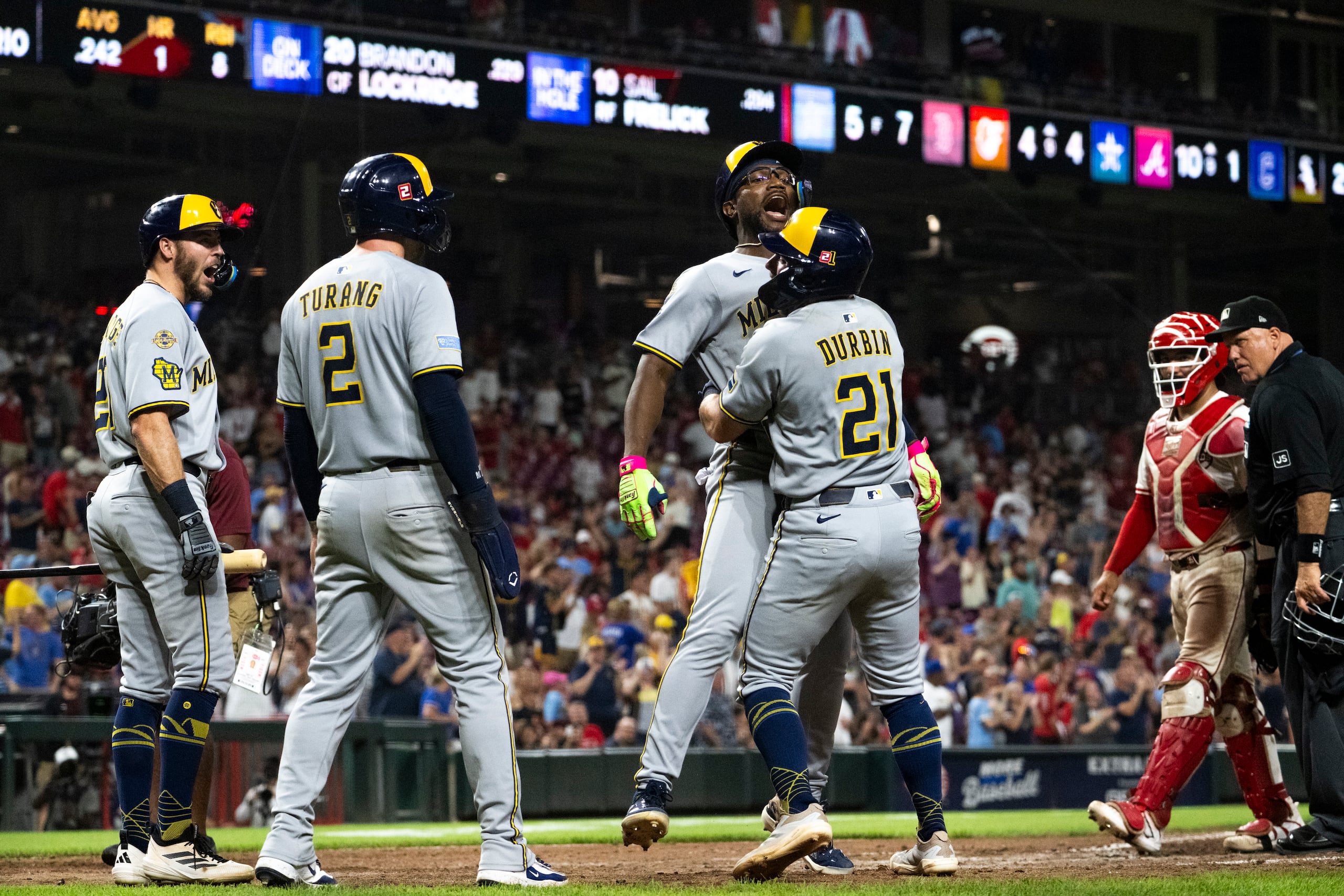 Andruw Monasterio, al centro, y Caleb Durbin (21) celebran un cuadrangular en entradas extras ante los Reds de Cincinnati.