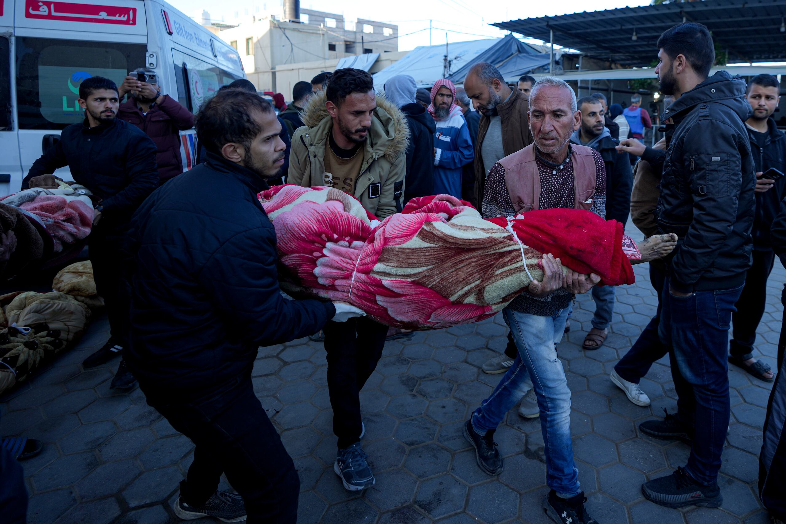 Palestinos llevan el cuerpo de un familiar muerto en el bombardeo israelí de la Franja de Gaza en un hospital de Deir al-Balah, domingo 15 de diciembre de 2024. (AP foto/Abdel Kareem Hana)