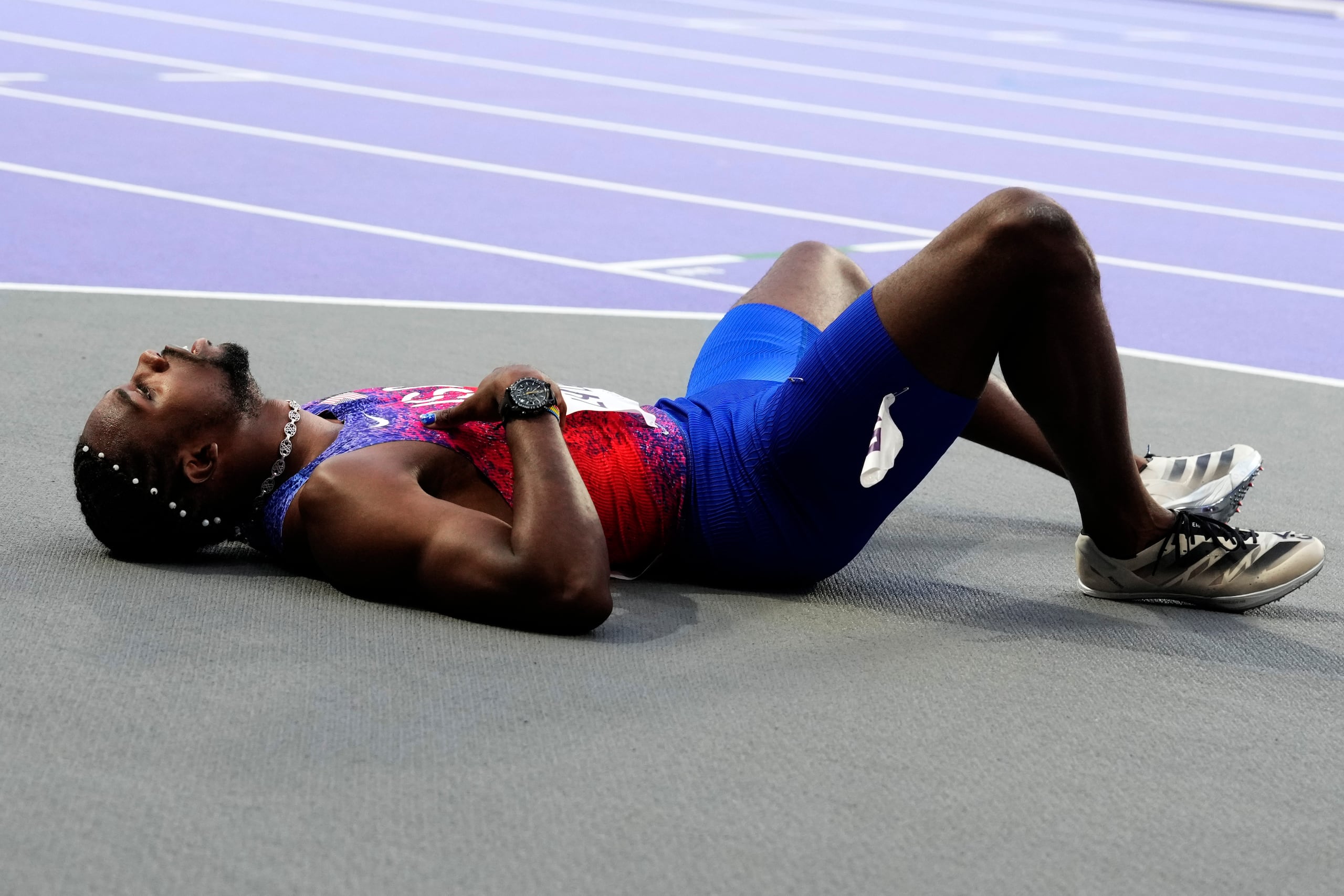 Noah Lyles, of the United States, lies on the track following the men's 200-meters final at the 2024 Summer Olympics, Thursday, Aug. 8, 2024, in Saint-Denis, France. (AP Photo/Petr David Josek)