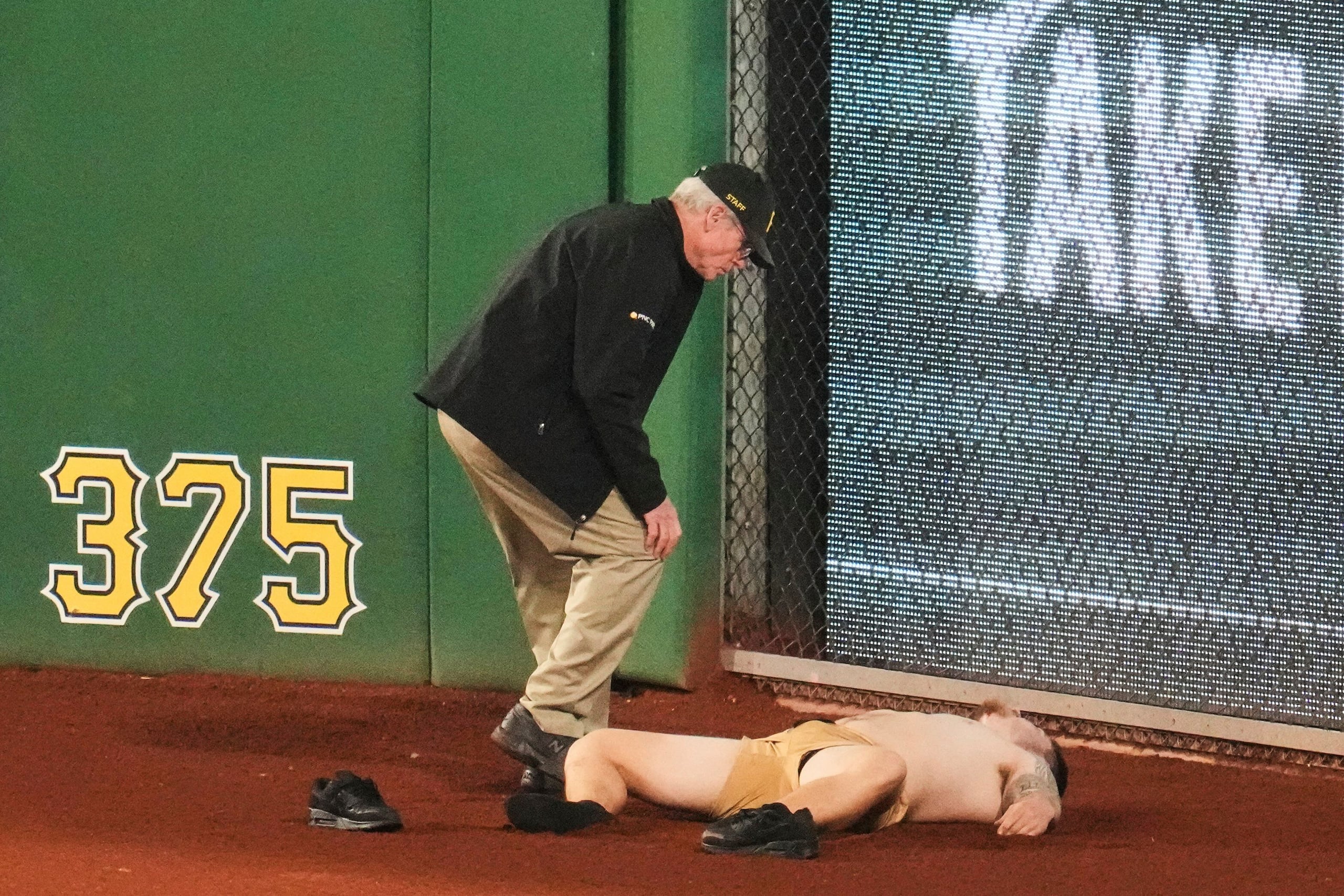 Un aficionado yace en el terreno de juego del jardín derecho del PNC Park tras caerse de las gradas durante la séptima entrada.