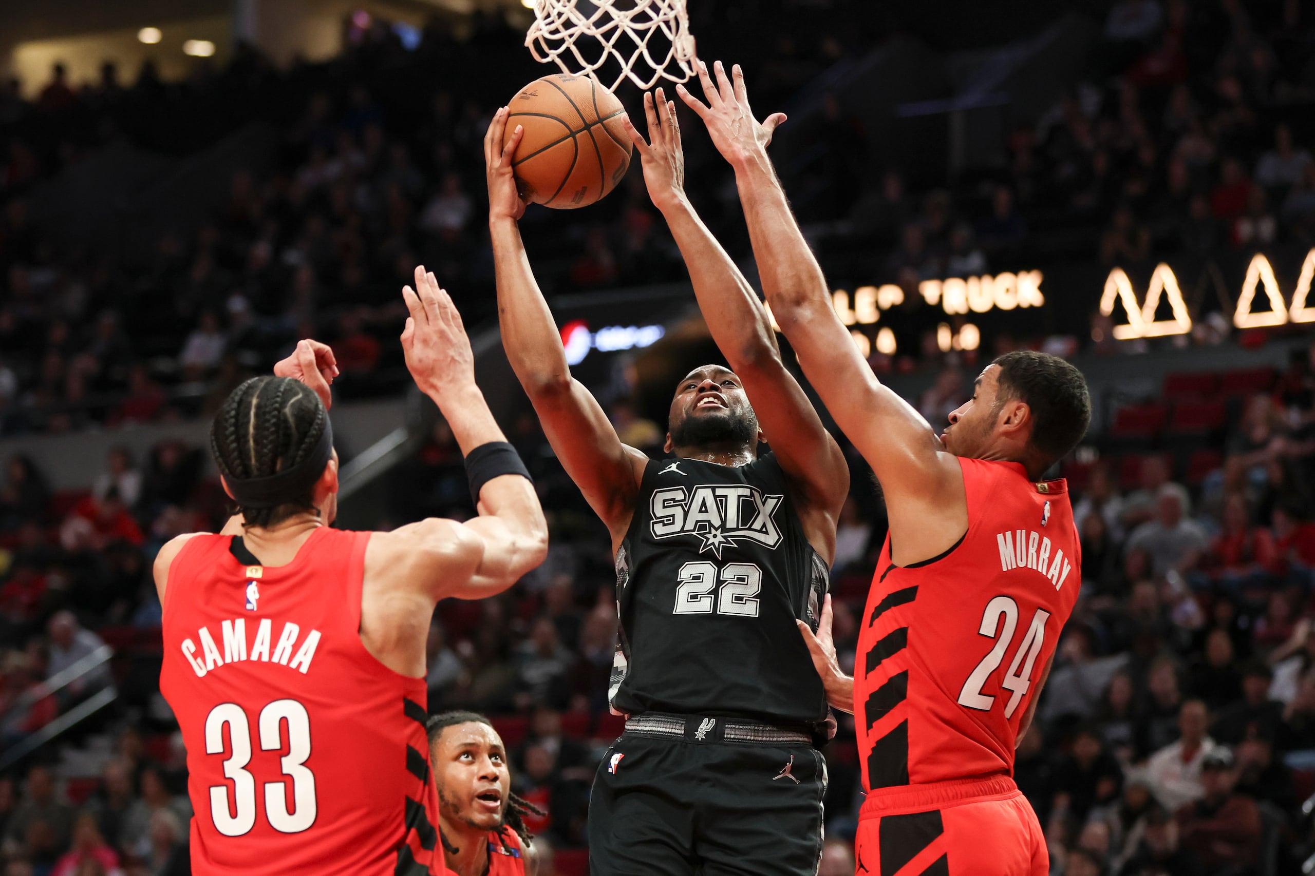 Malaki Branham (22), de los Spurs de San Antonio, busca encestar entre Toumani Camara (33) y Kris Murray (24), de los Trail Blazers de Portland, durante la segunda mitad del juego de baloncesto de la NBA.