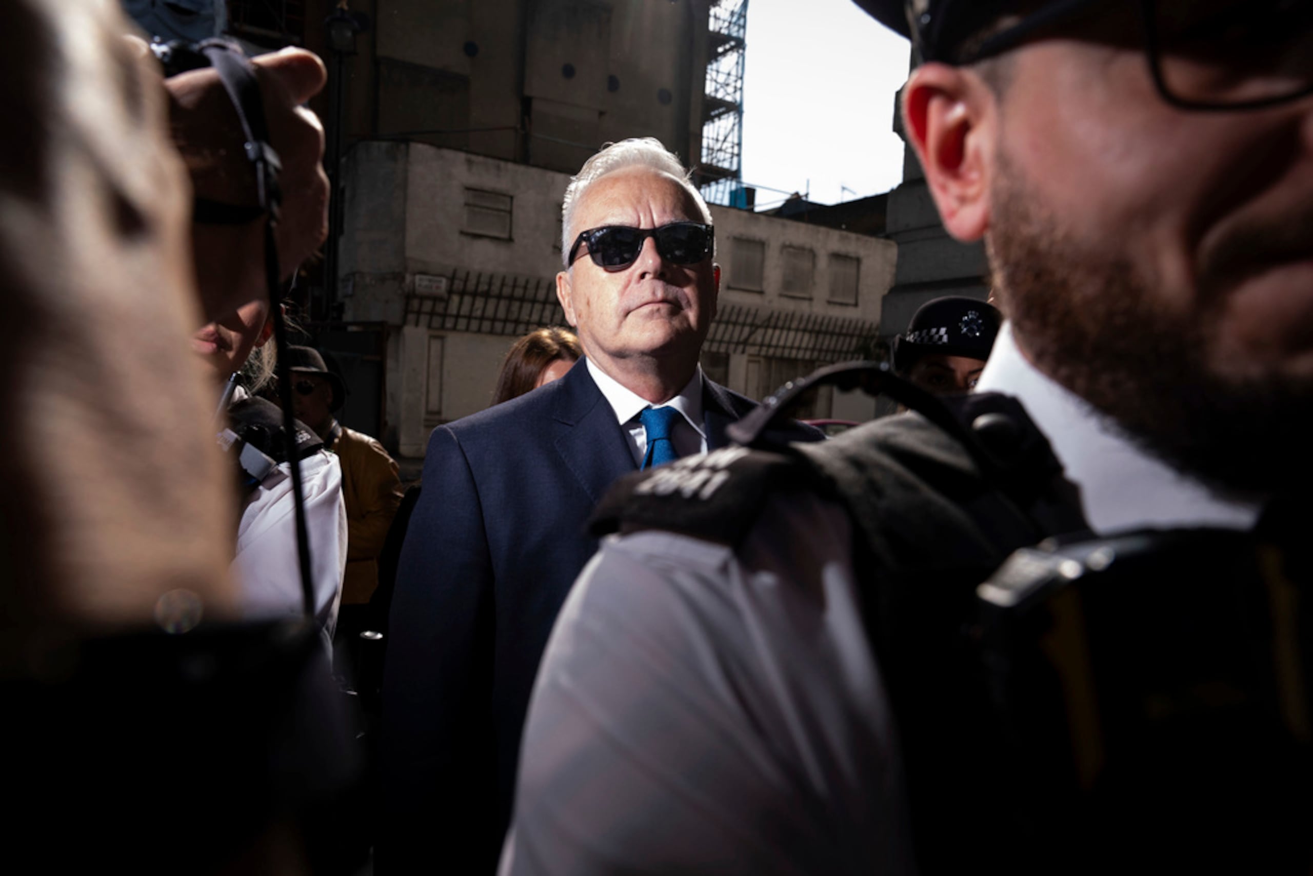 Vestido de oscuro y con gafas de sol, Huw Edwards llegó a la Corte de Magistrados de Westminster flanqueado por policías, entre una gran expectación mediática por un caso que conmociona al Reino Unido.