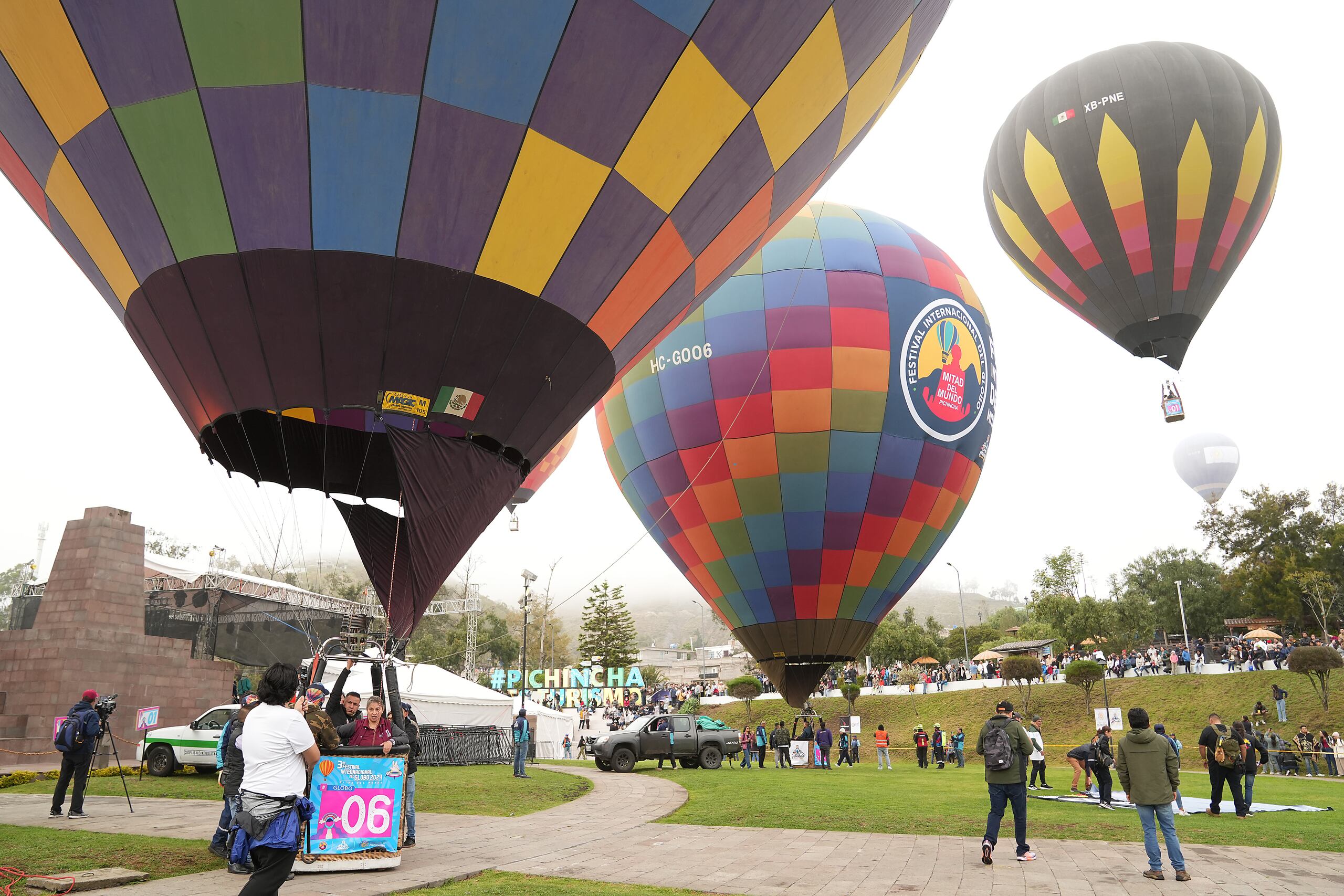 Personas observan varios globos aerostáticos durante el Festival Internacional del Globo en la Mitad del Mundo, este sábado, en Quito (Ecuador). EFE/ Vicente Costales