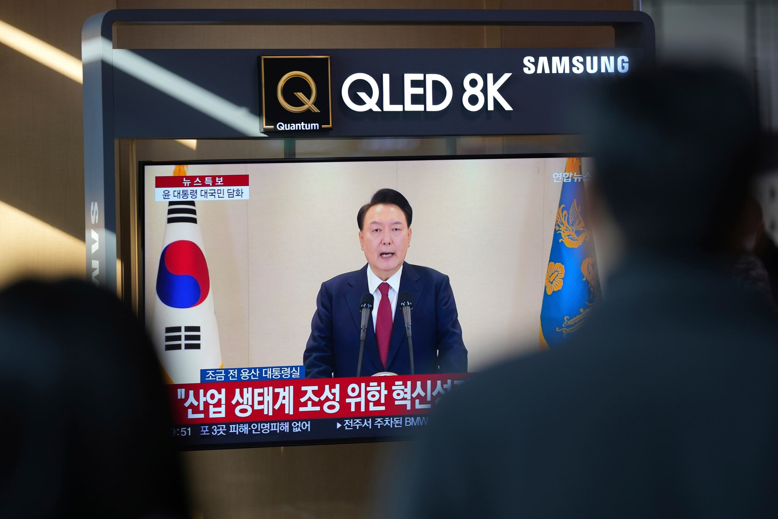 Personas ven una pantalla de TV que muestra una transmisión en vivo de un discurso del presidente de Corea del Sur, Yoon Suk Yeol, en la estación de trenes de Seúl el jueves 12 de diciembre de 2024. (AP Foto//Lee Jin-man)