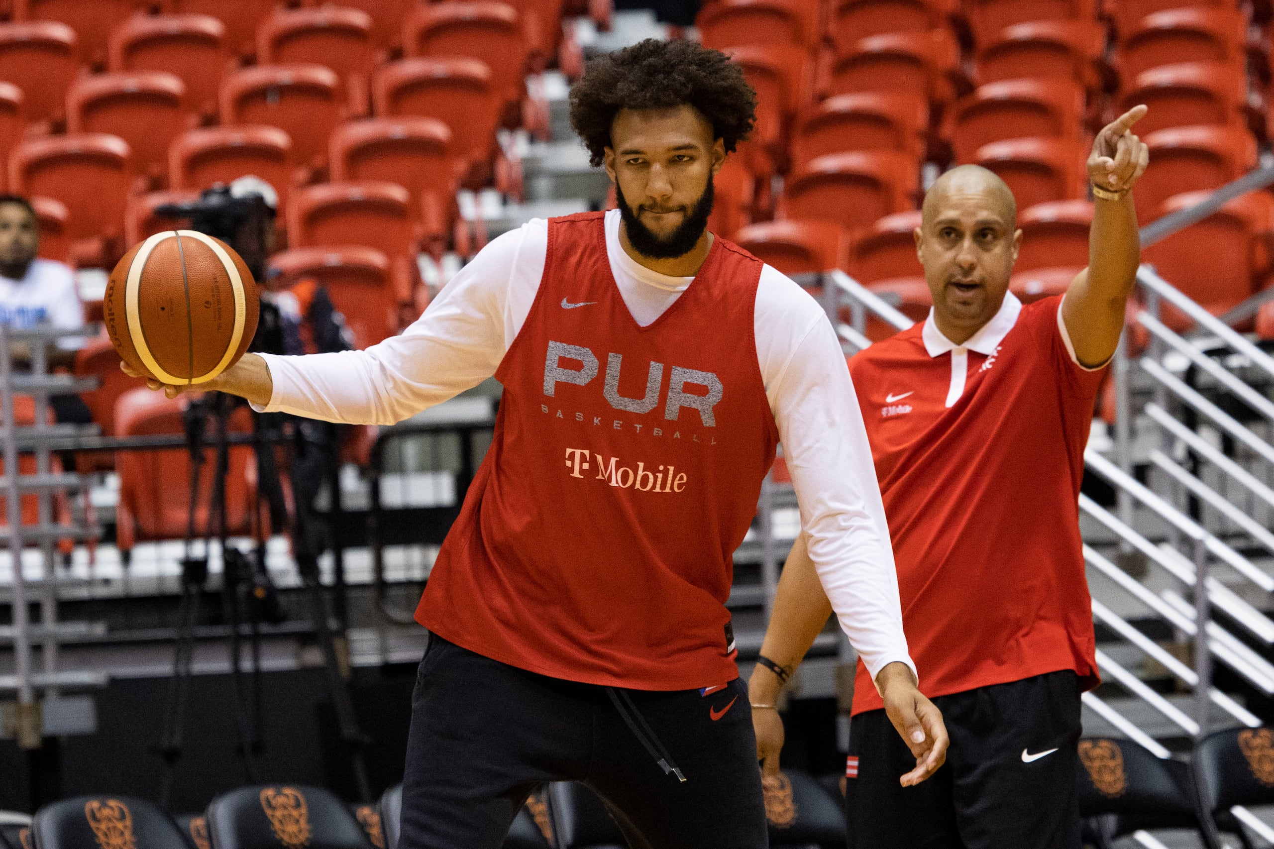 George Conditt mueve un balón mientras Nelson Colón, al fondo, imparte instrucciones.