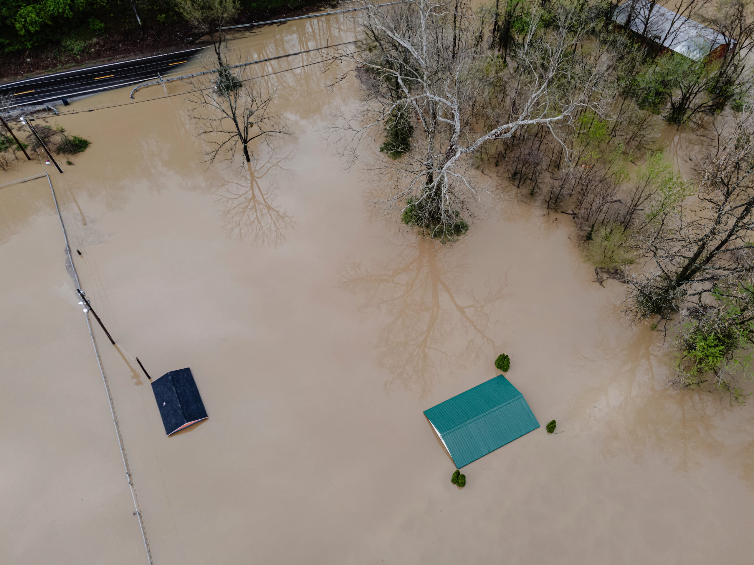 Vista aérea de edificios y vehículos en una propiedad inundada el sábado 5 de abril de 2025, en Frankfort, Kentucky. (AP Foto/Jon Cherry)