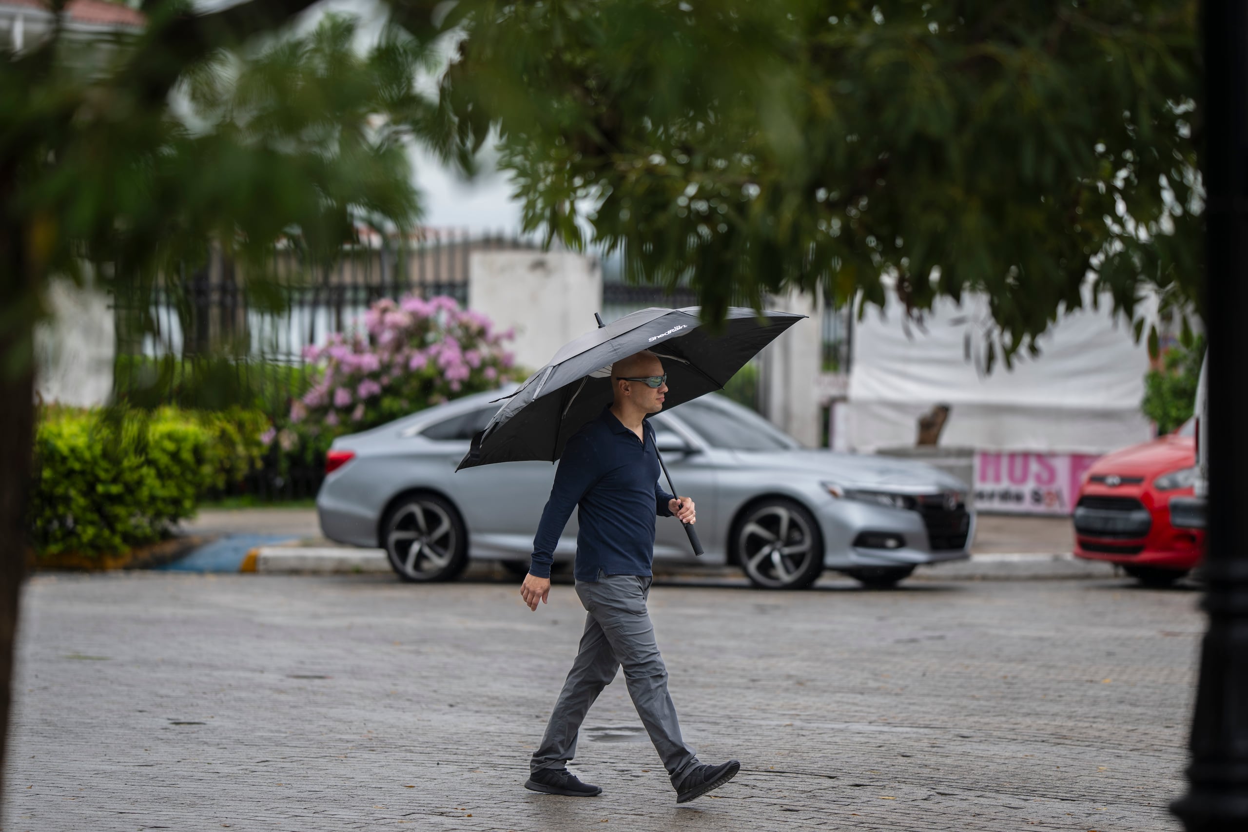 Un hombre camina por el Paseo de la Princesa del Viejo San Juan durante tiempo lluvioso.