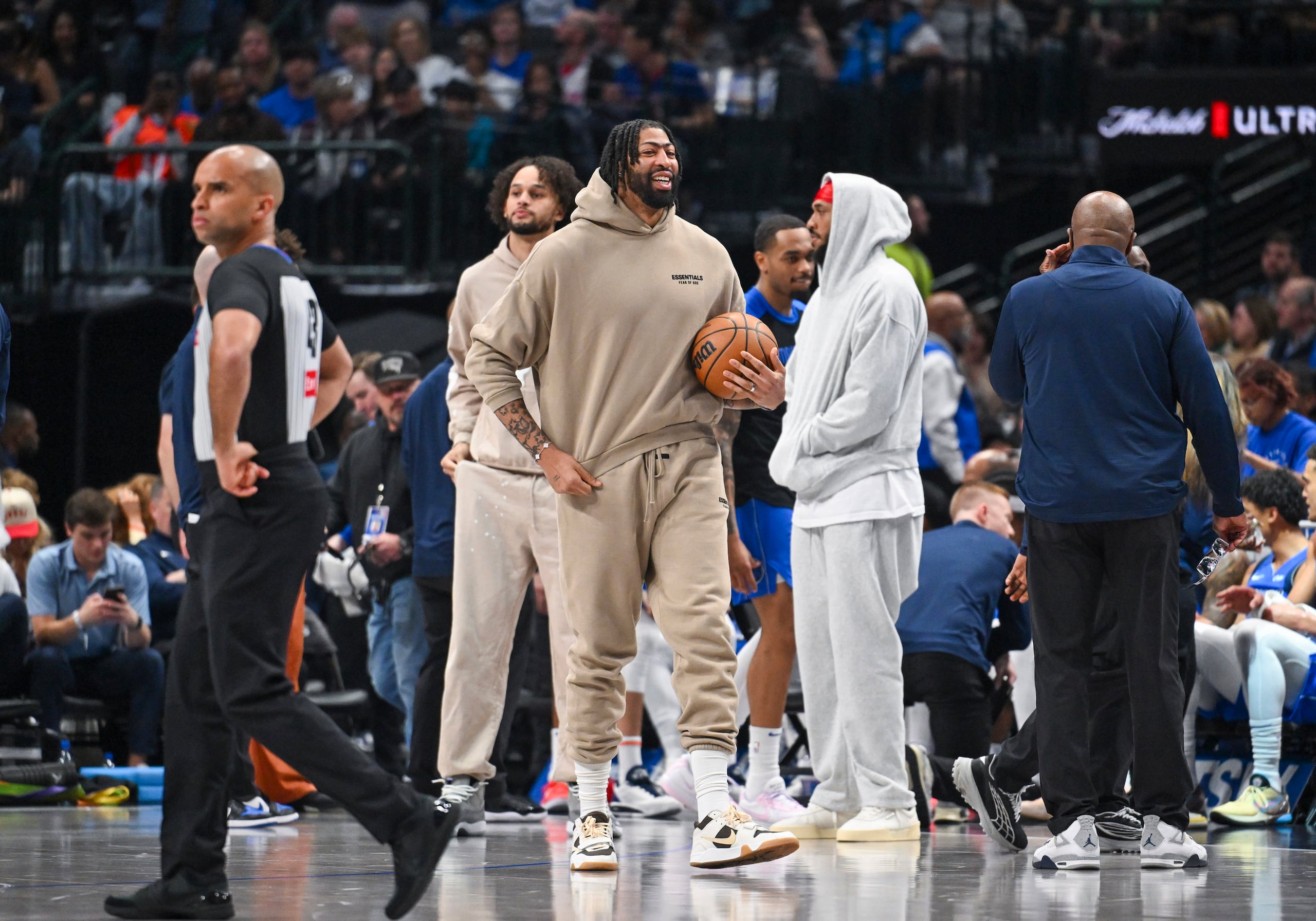 Anthony Davis, centro, de los Mavaricks de Dallas, con ropa de calle debido a una lesión, convive en la duela con sus compañeros durante la primera mitad del juego de baloncesto de la NBA contra los Pistons de Detroit, el viernes 21 de marzo de 2025, en Dallas, Teas.