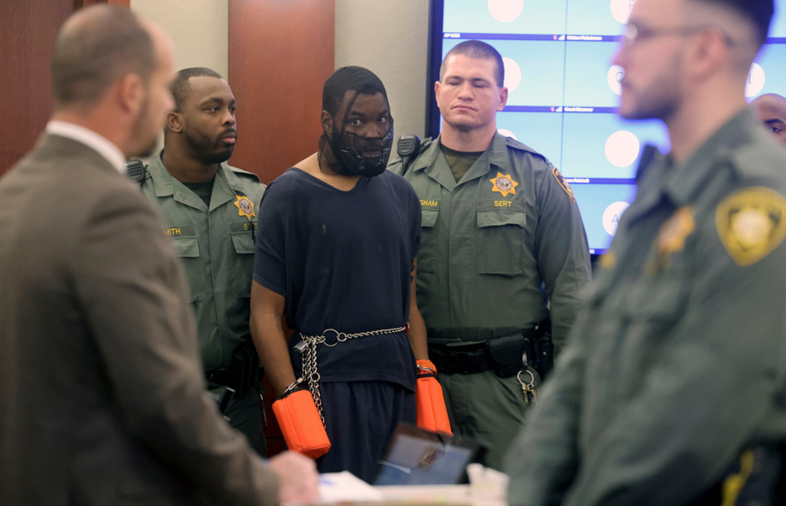 Deobra Redden estaba flanqueado por guardias de seguridad de la cárcel, con una máscara que le cubría parte del rostro y guantes naranjas en las manos.