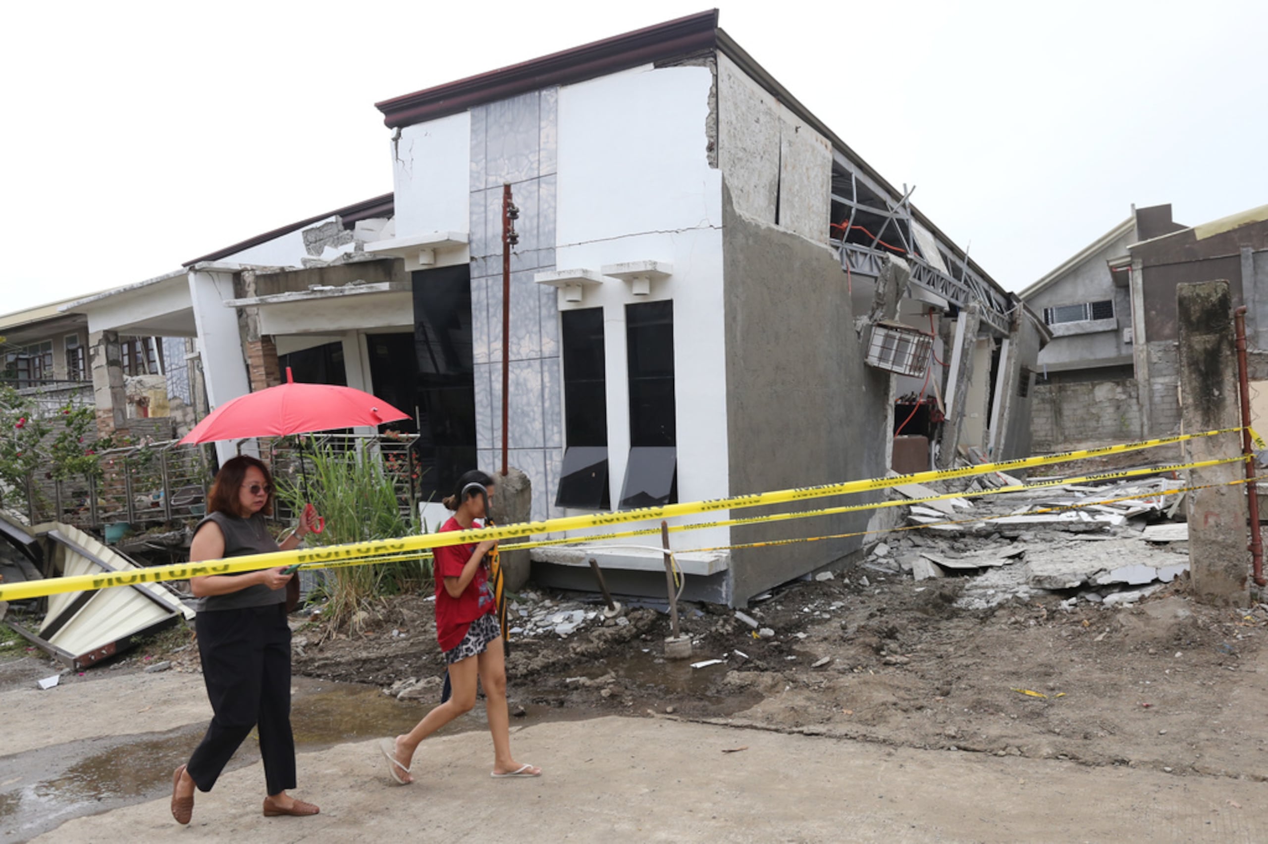 Dos mujeres pasan por delante de una casa dañada tras un potente sismo en la ciudad de Davao, en el Sur de Filipinas, el 10 de octubre de 2025.