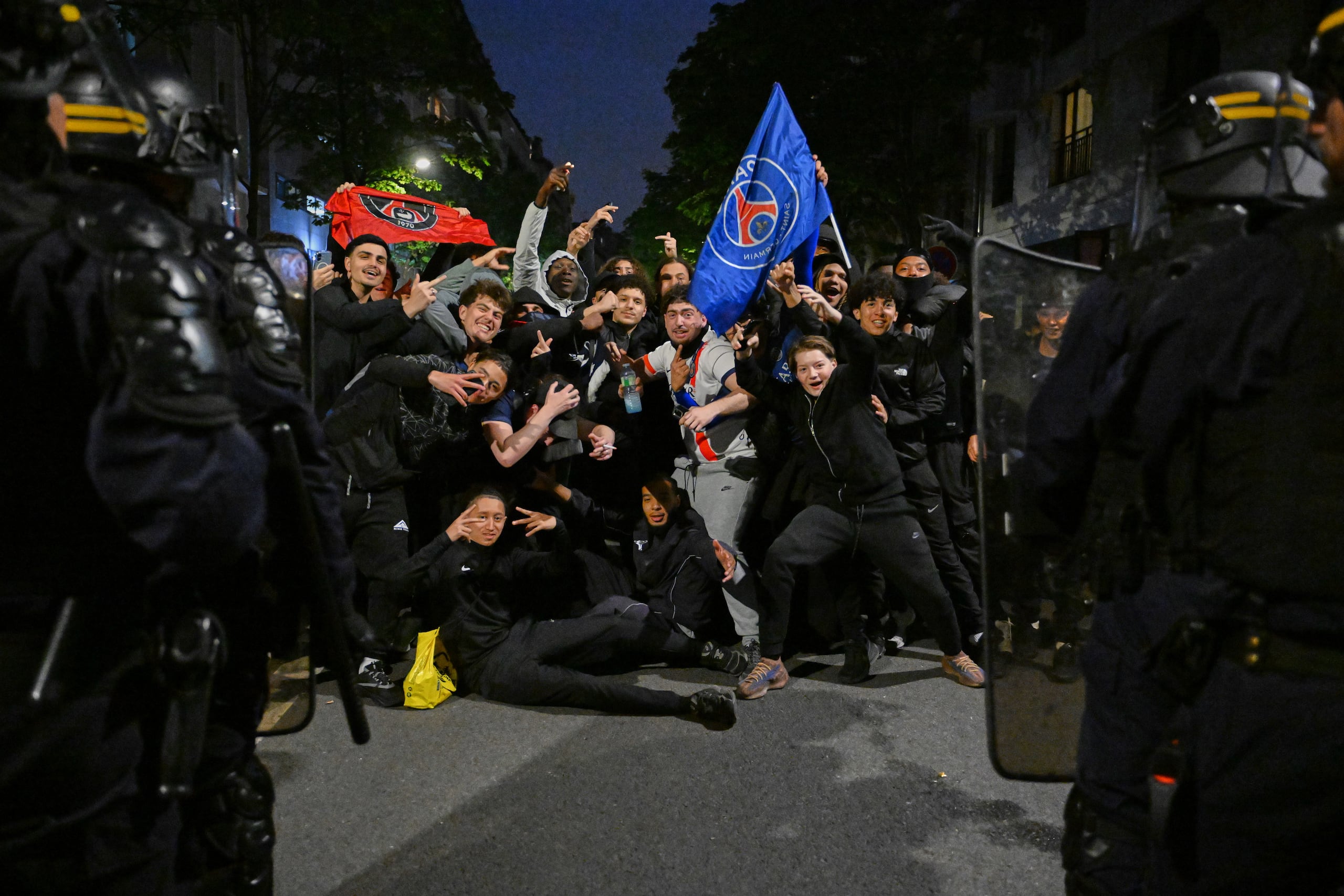 Hinchas del Paris Saint-Germain frente a policías al celebrar la victoria ante el Bayern Múnich en las semifinales de la Liga de Campeones, el jueves 7 de mayo de 2026, en París. (AP Foto/Emma Da Silva)