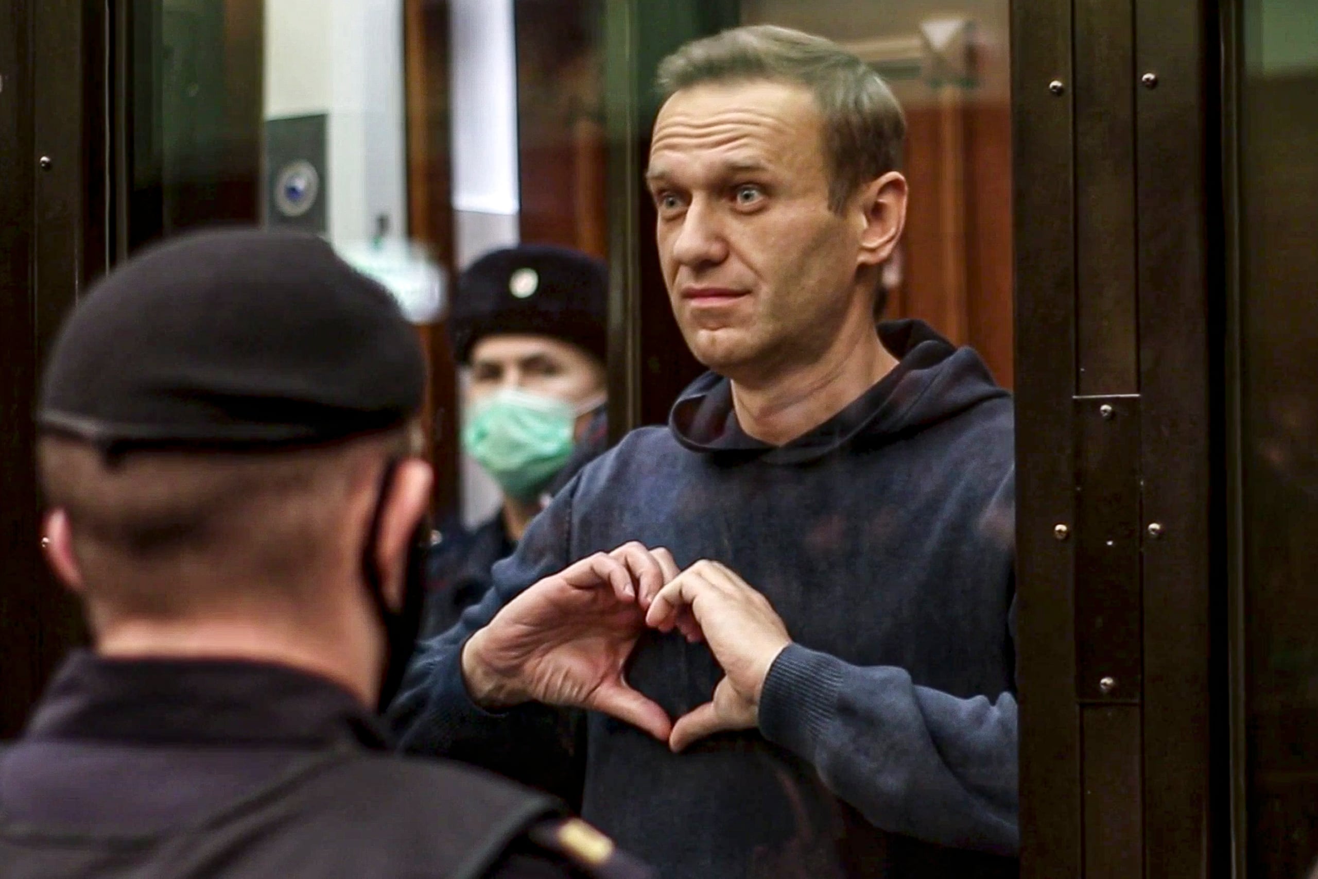 En esta imagen de archivo, tomada de un video distribuido por la Corte de la Ciudad de Moscú, el 2 de febrero de 2021, el líder opositor ruso Alexei Navalny hace un corazón con sus manos desde el espacio reservado para los acusados durante una vista en el tribunal, en Moscú, Rusia.