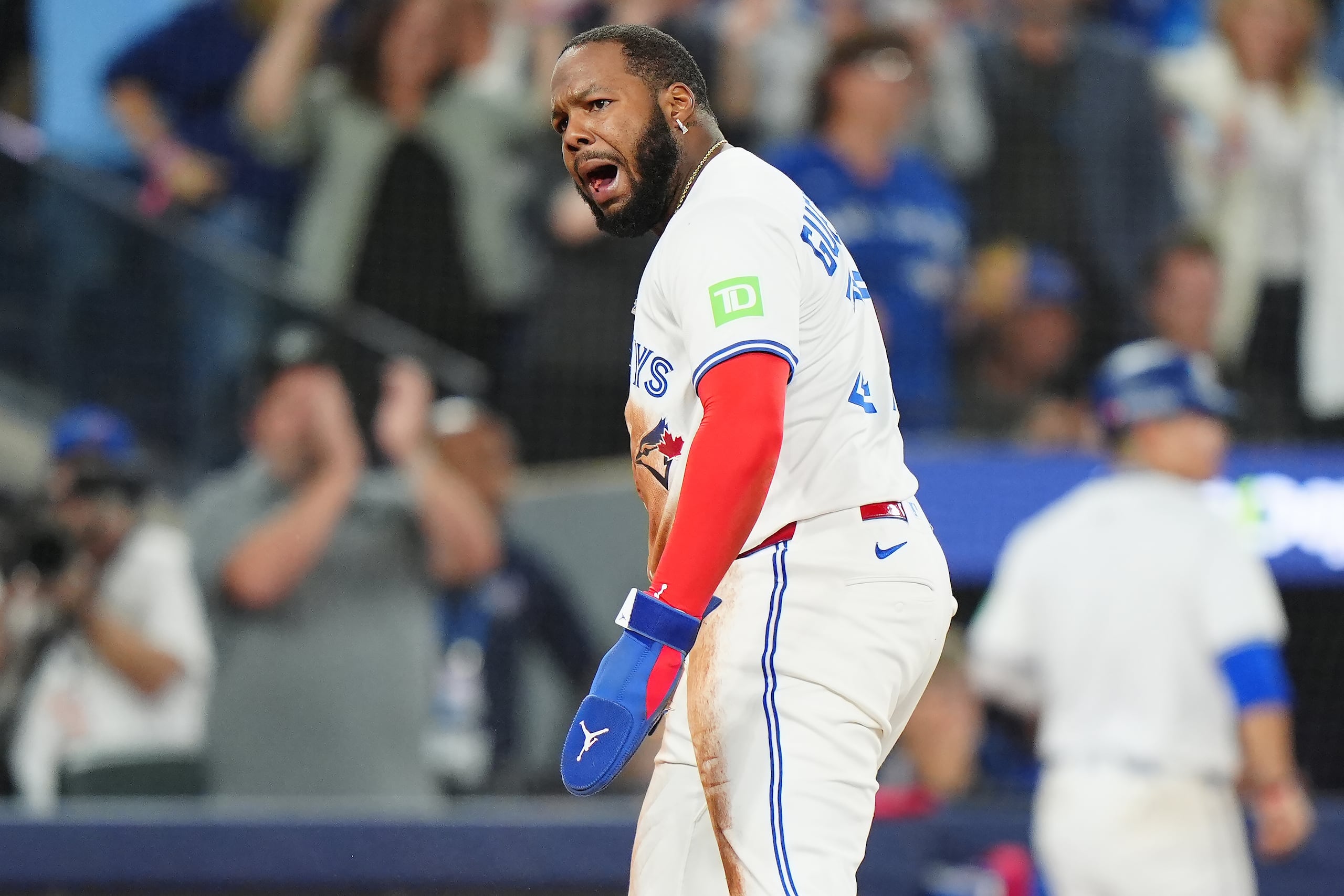 Toronto Blue Jays' Vladimir Guerrero Jr. (27) celebrates scoring after a throwing error at third base by Seattle Mariners catcher Cal Raleigh (not shown) during seventh inning MLB American League Championship Series game 6 baseball action in Toronto, Sunday, Oct. 19, 2025. (Frank Gunn/The Canadian Press via AP)